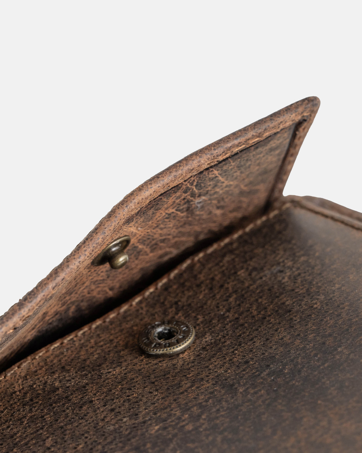 Close-up of the metal snap button on a earth leather wallet without ID flap
