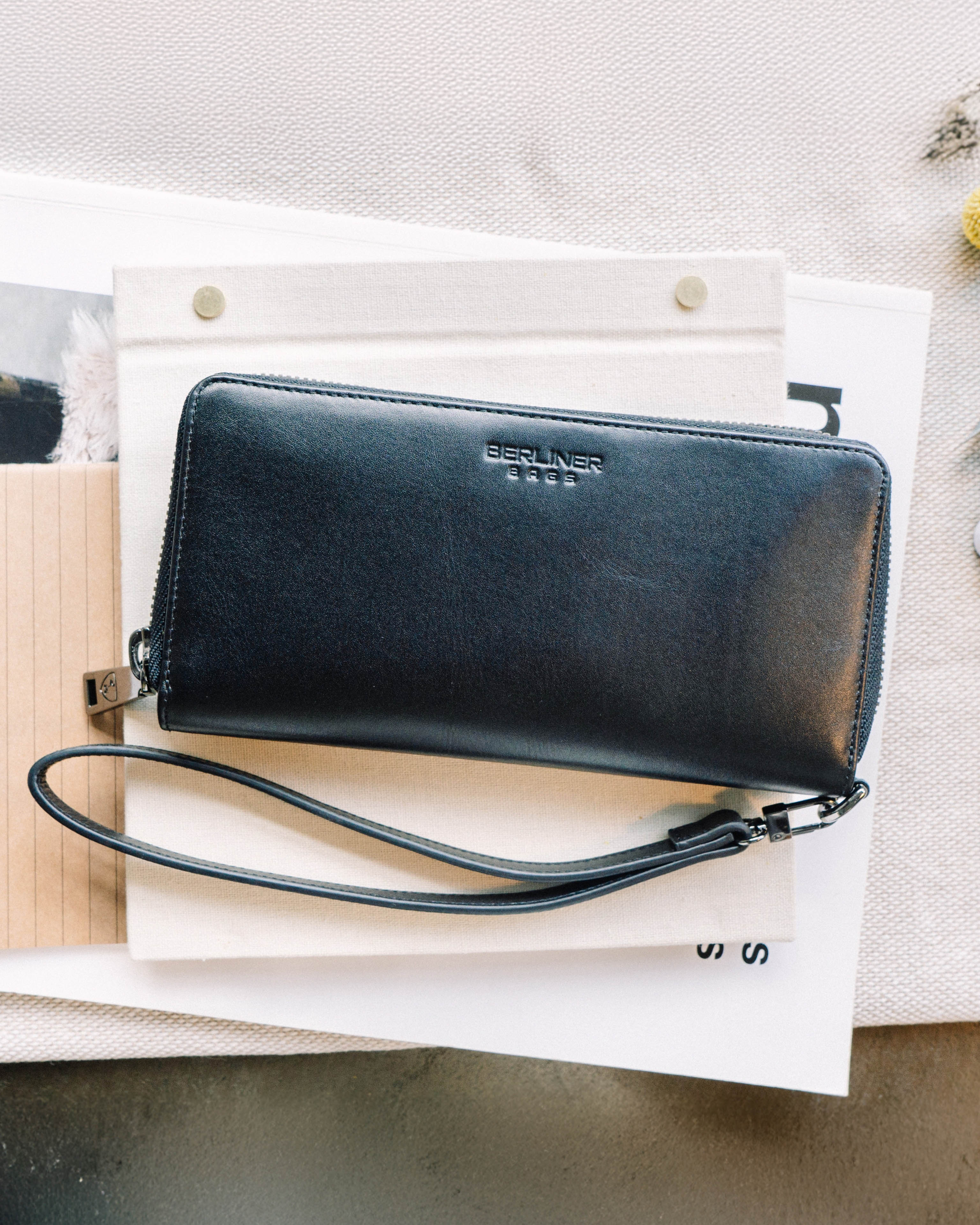 A black emboss leather wallet featuring a detachable wrist strap