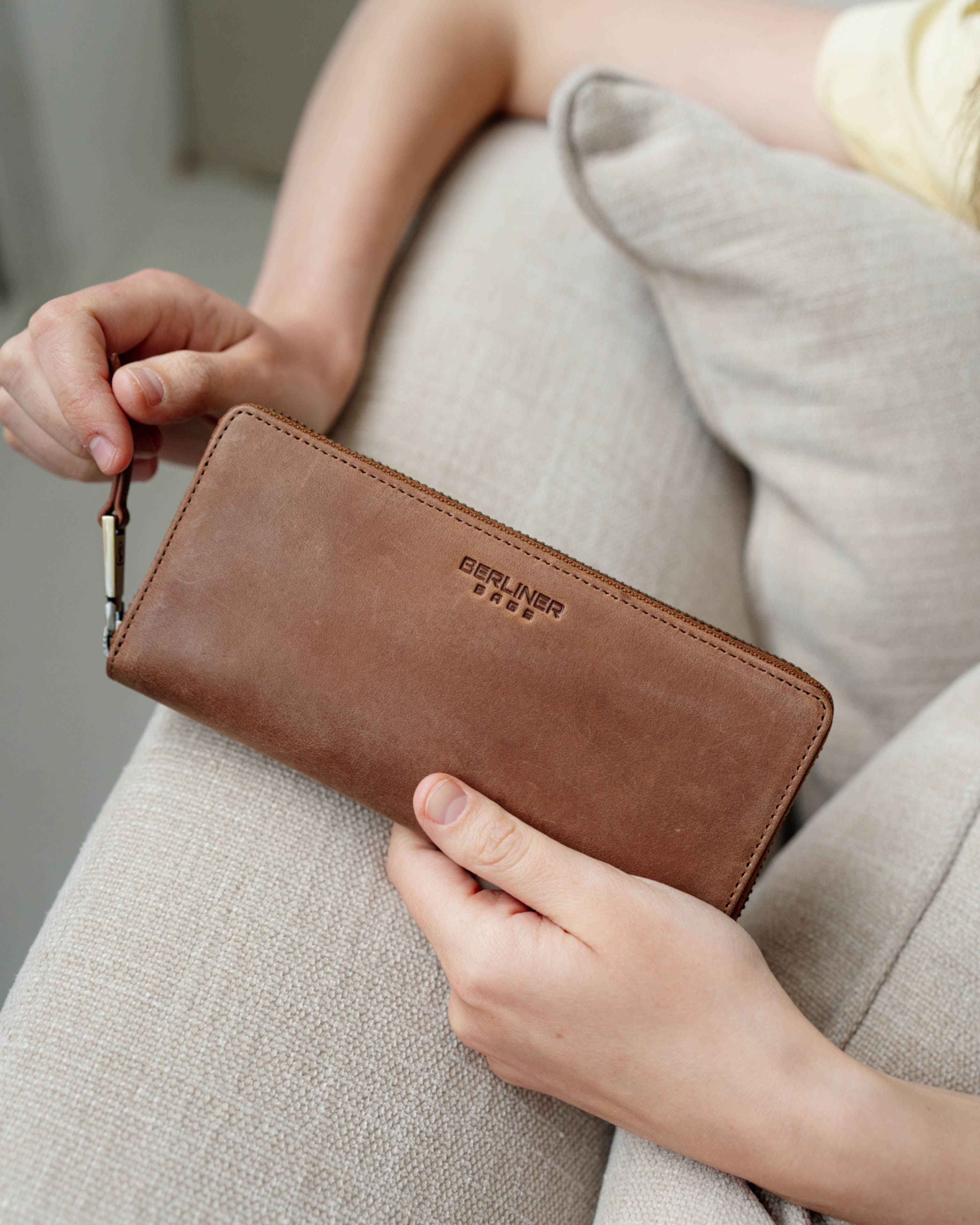 A person holding a camel leather wallet