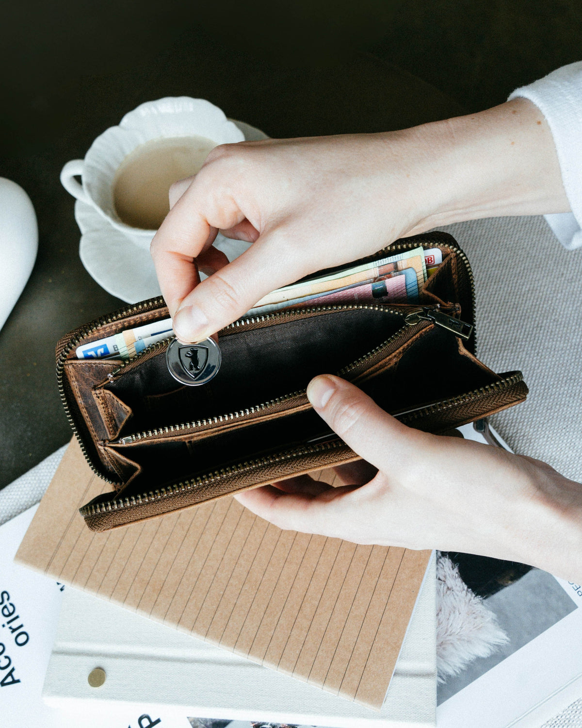 Person holding a walnut leather wallet with a branded coin.