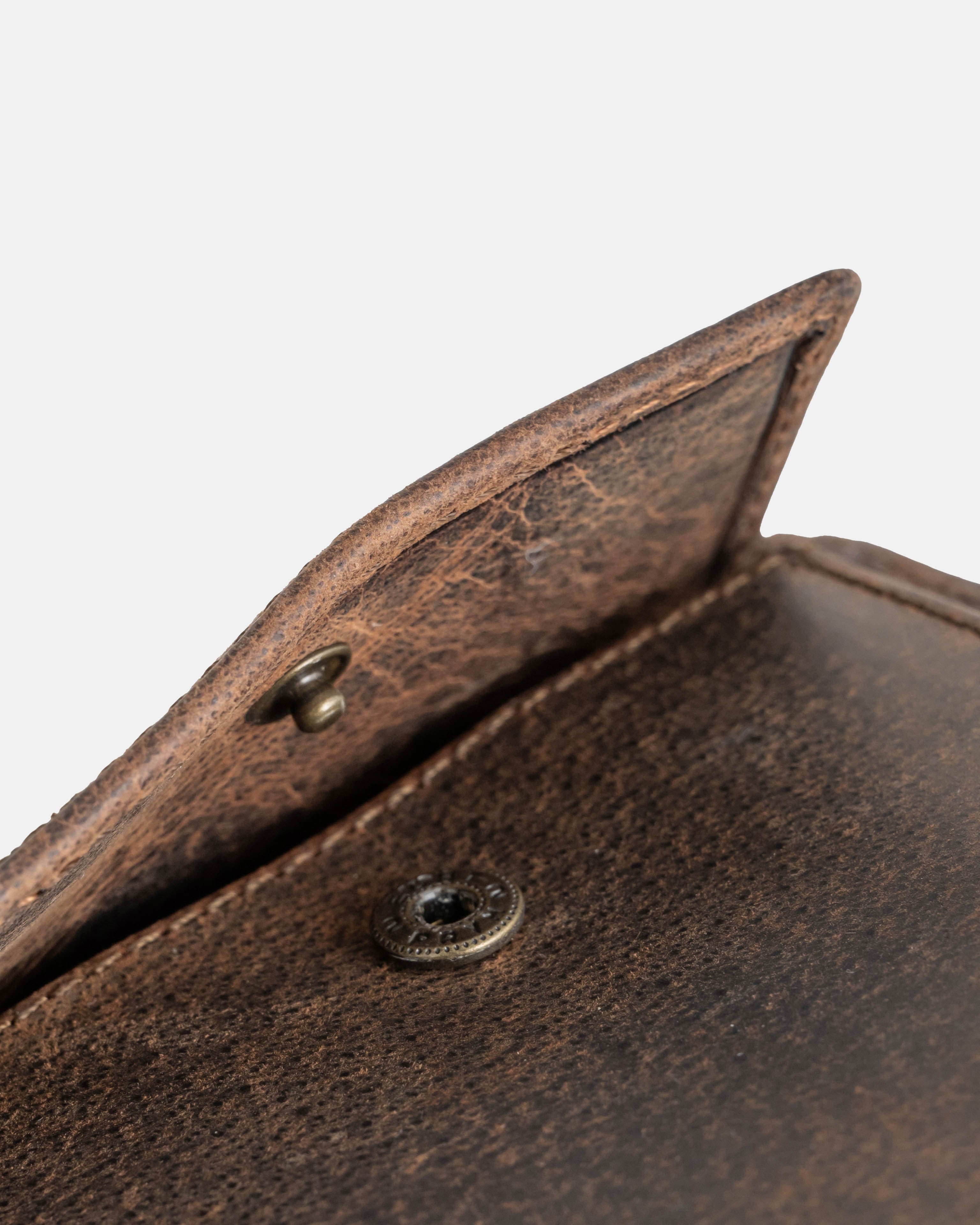 Close-up of the metal snap button on a earth leather wallet with ID flap