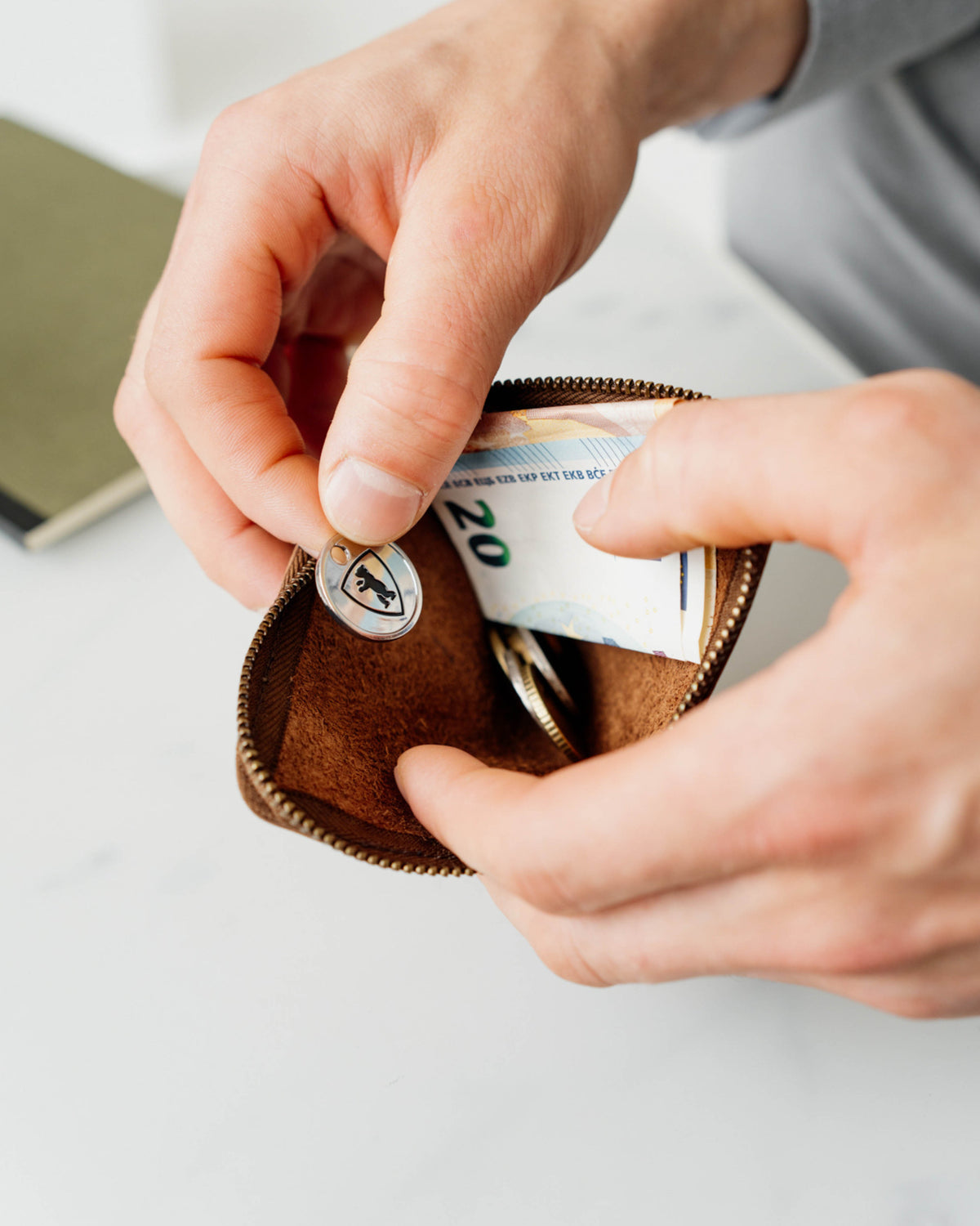 Person putting branded button in to a walnut leather wallet