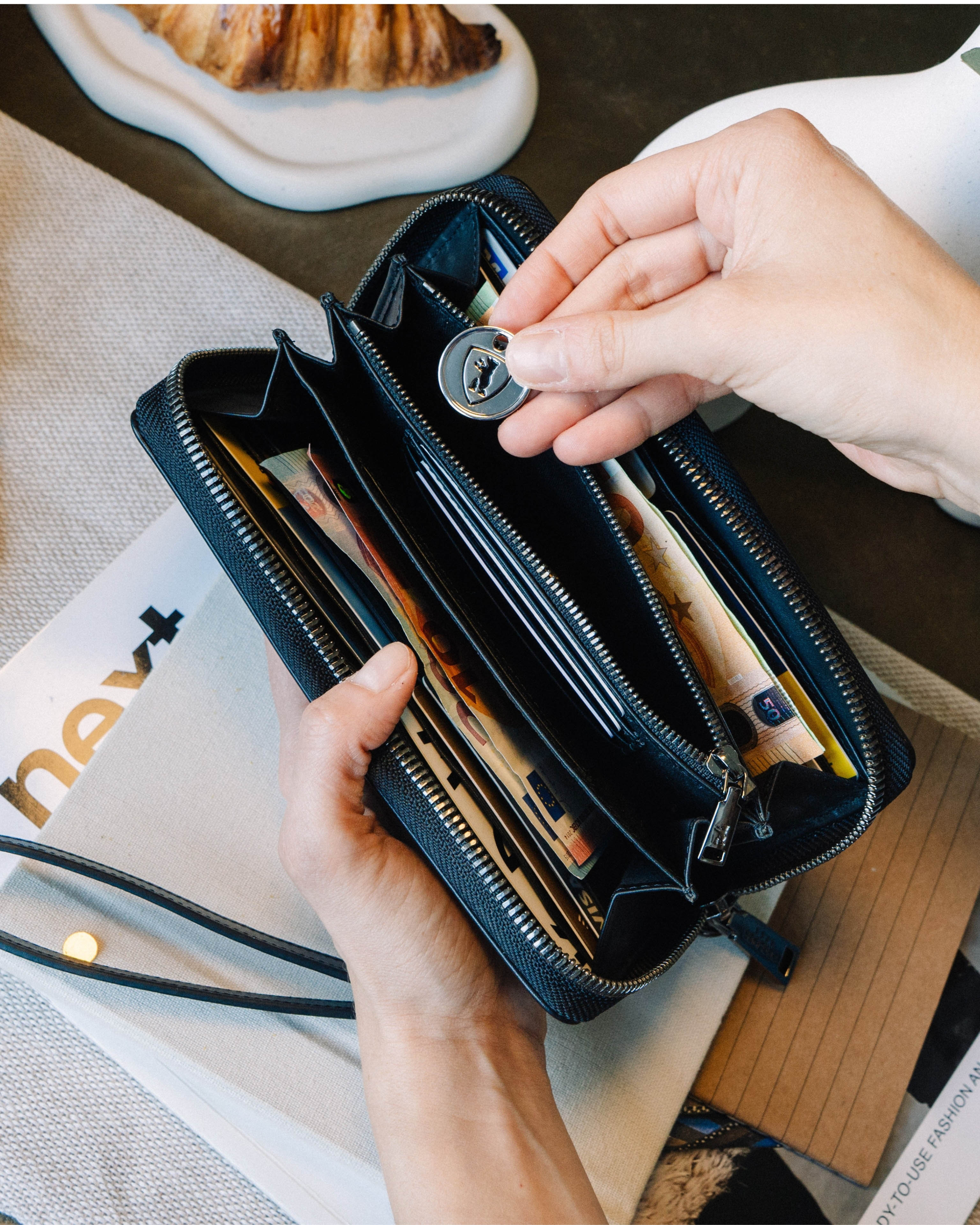 Placing a coin inside an open black emboss leather wallet