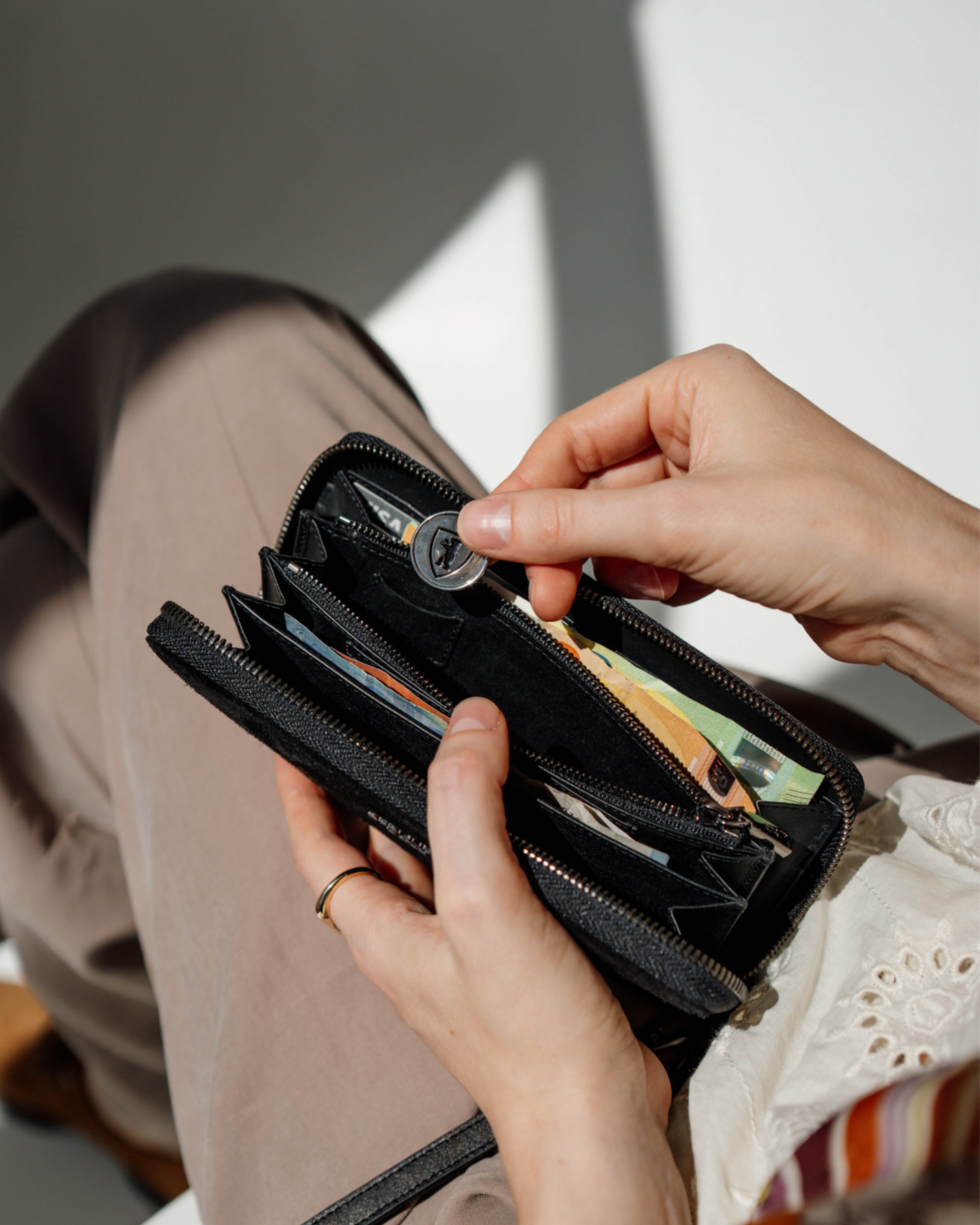 Placing a coin in inside an open suede black leather wallet