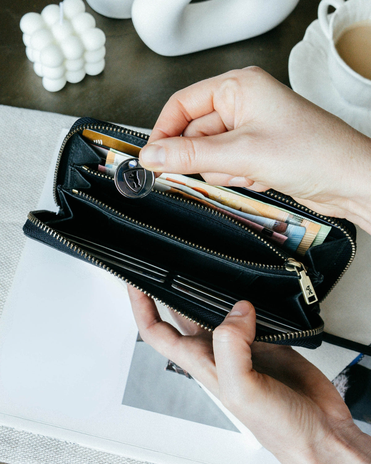Person holding a walnut leather wallet with a branded coin.