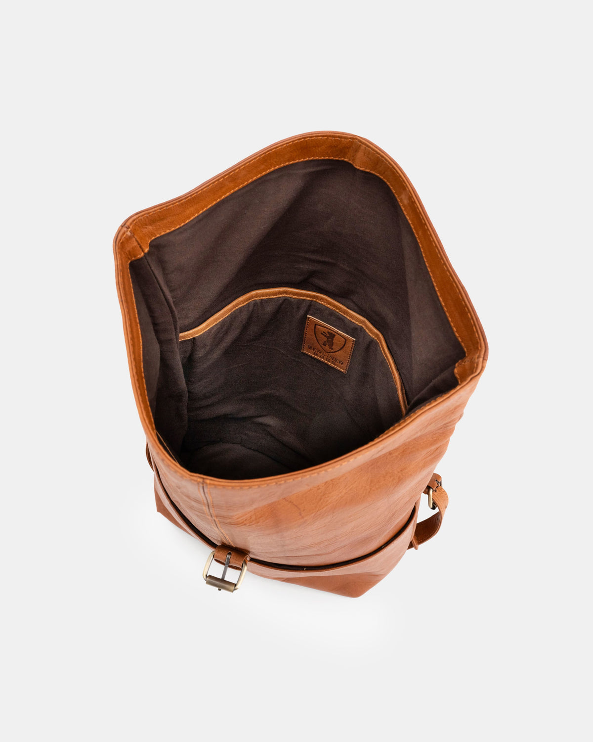Top-down view of open vintage leather roll-top backpack showing interior compartment.