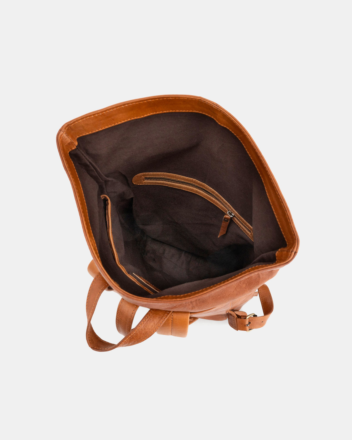 Top-down view of open vintage leather roll-top backpack showing interior compartment.