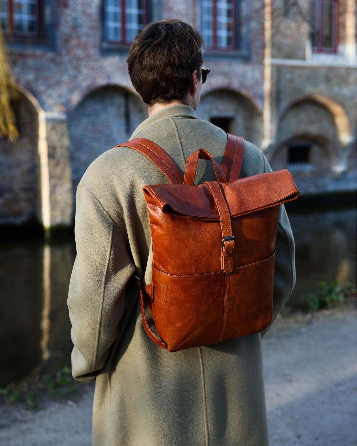 Rear lifestyle shot of man wearing vintage leather roll-top backpack