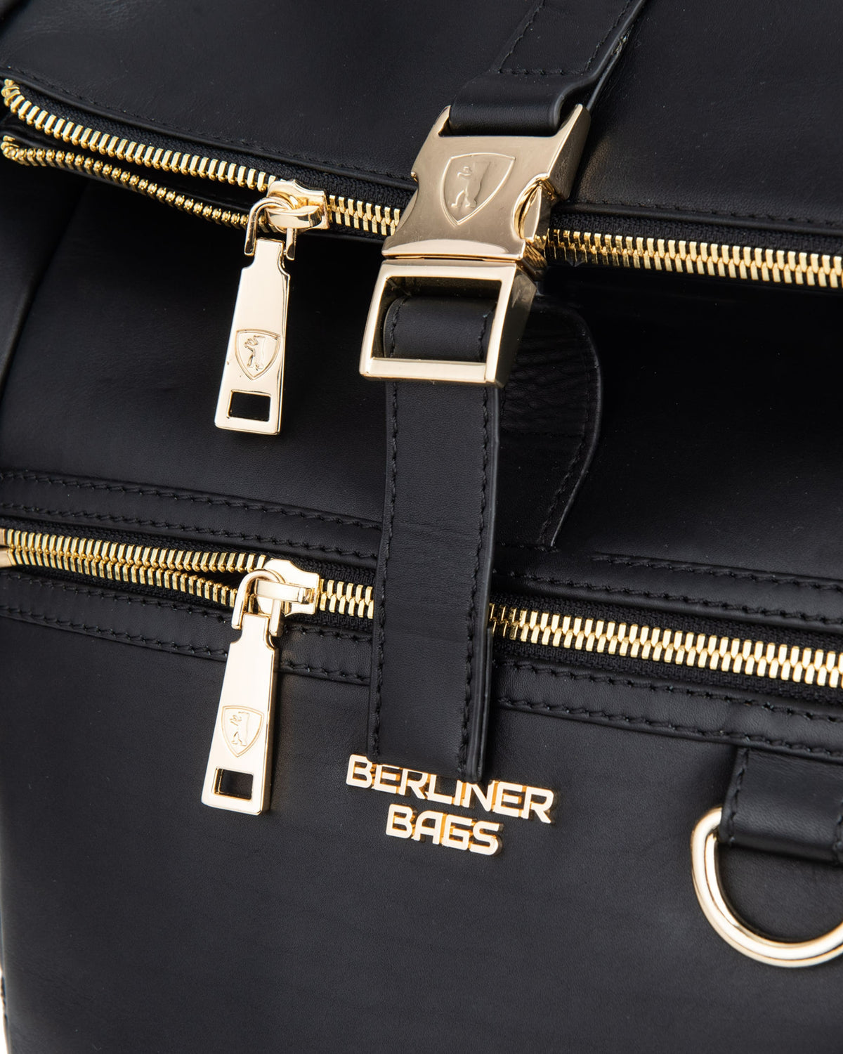 Close-up of black backpack highlighting gold metal buckle and zipper
