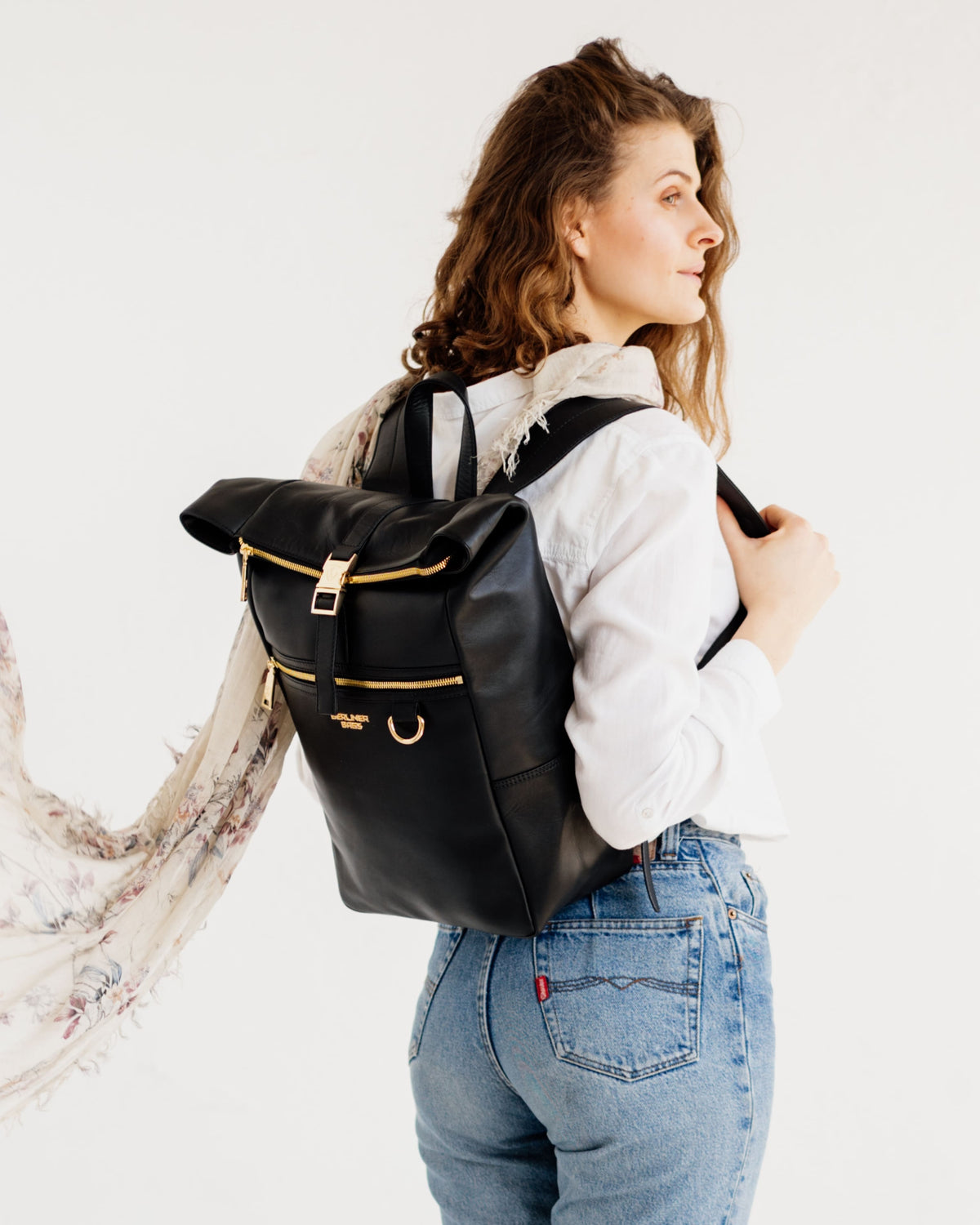Woman wearing a black-gold roll-top leather backpack