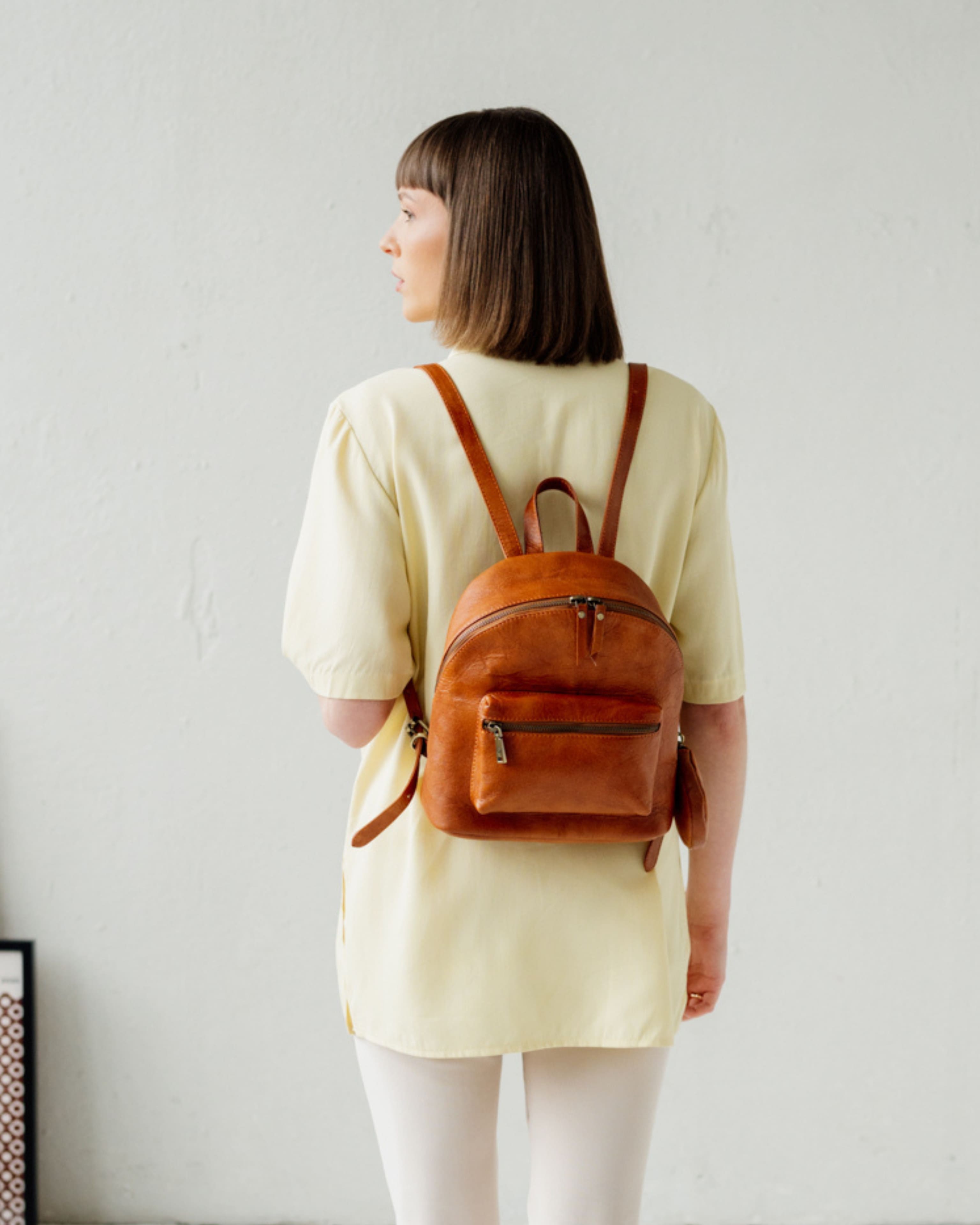 Rear view of woman wearing vintage leather zip-around backpack with coin purse.