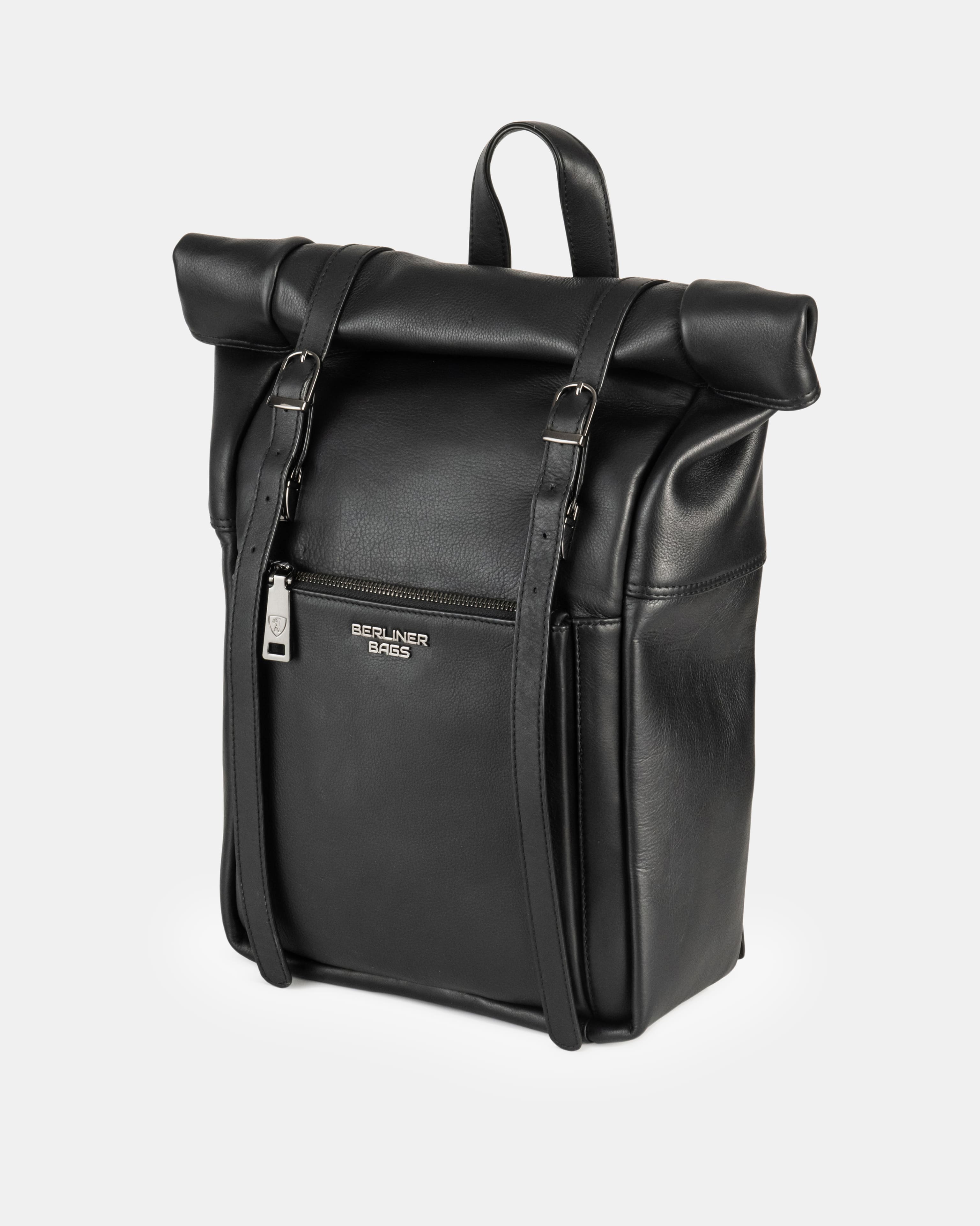 Three-quarter product view of a black leather roll-top backpack showcasing dual vertical buckle straps and a top handle