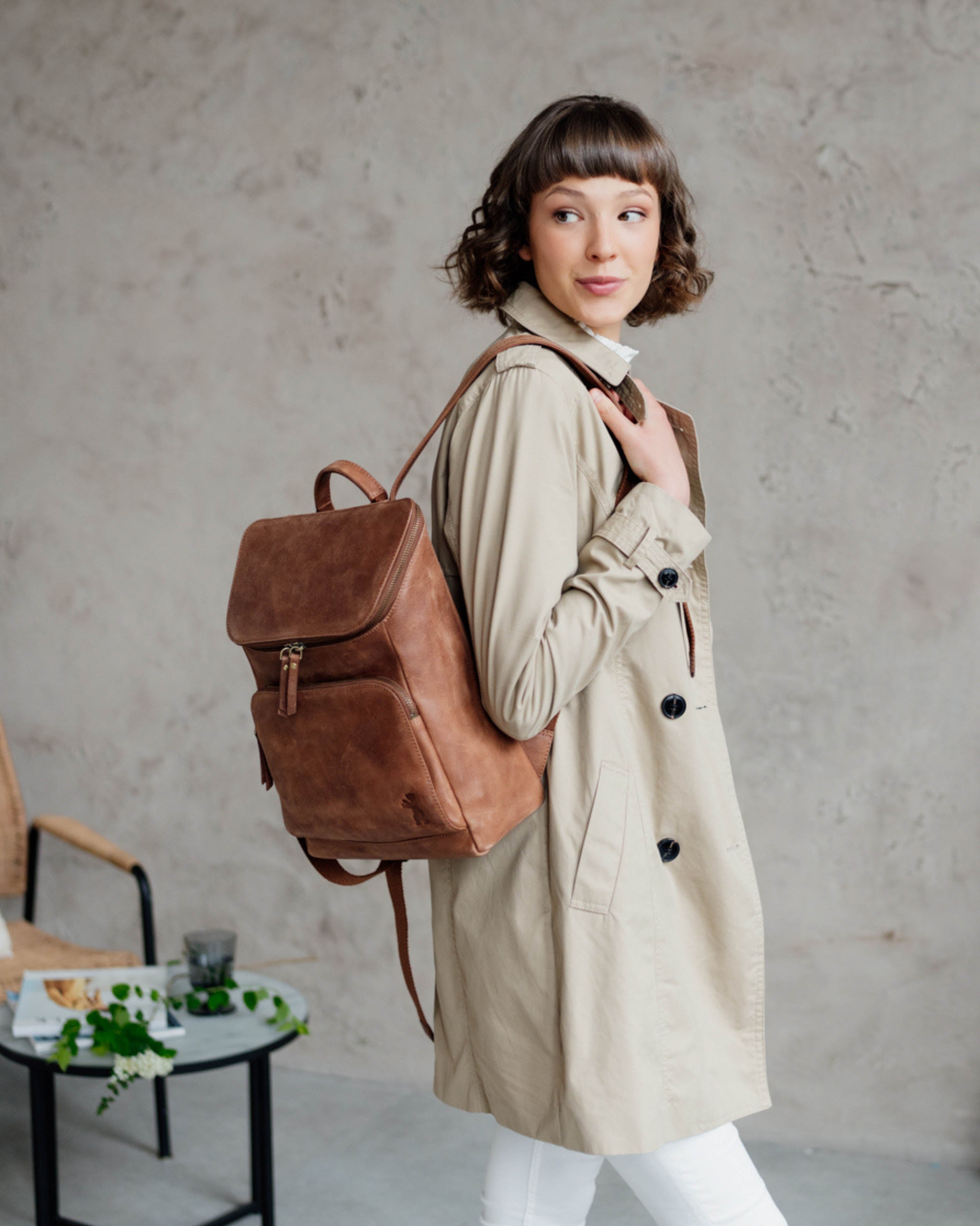 Three-quarter lifestyle view of woman wearing camel leather backpack.
