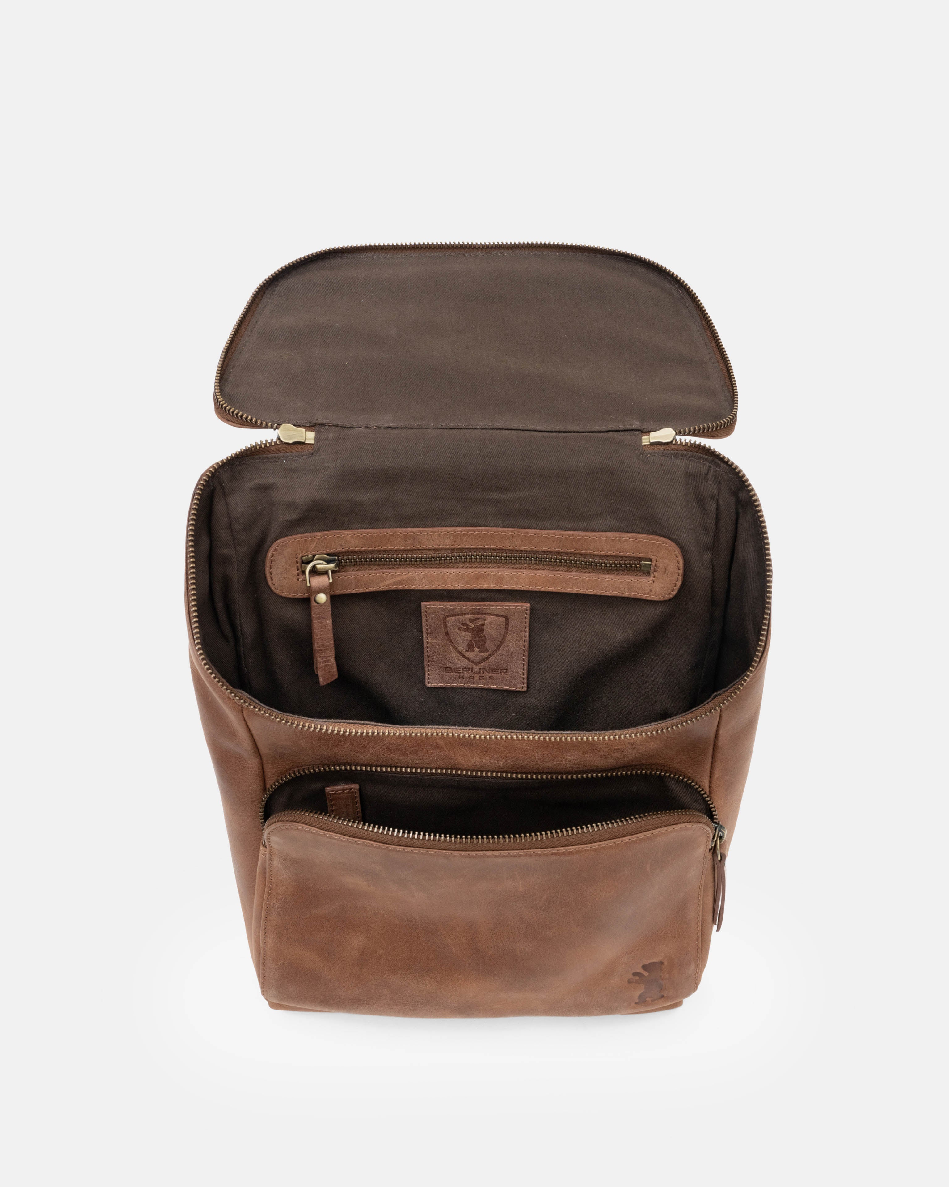 Top-down view of open camel leather zip-around backpack showing interior compartment