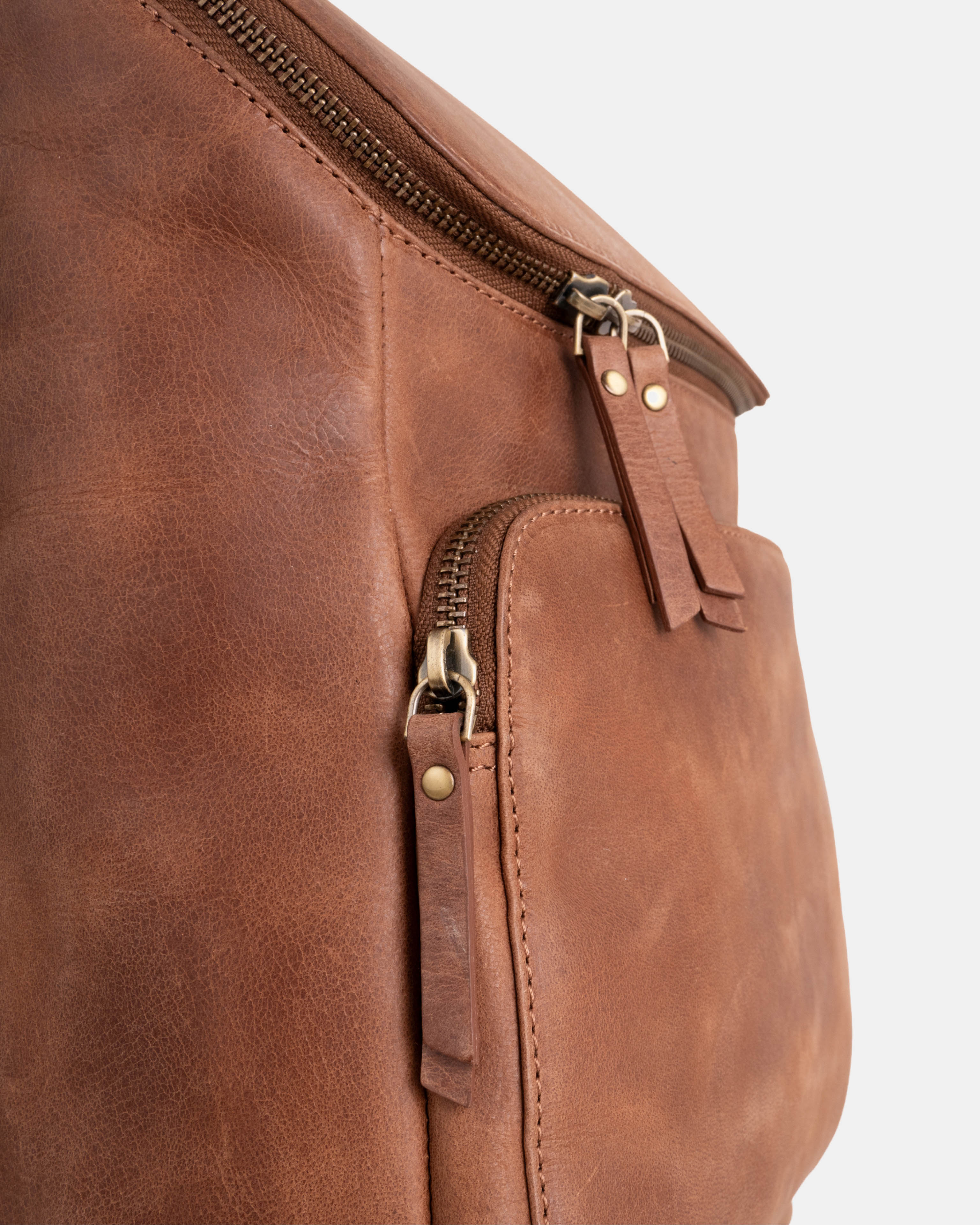 Close-up view of camel backpack highlighting leather zip pulls and metallic zippers