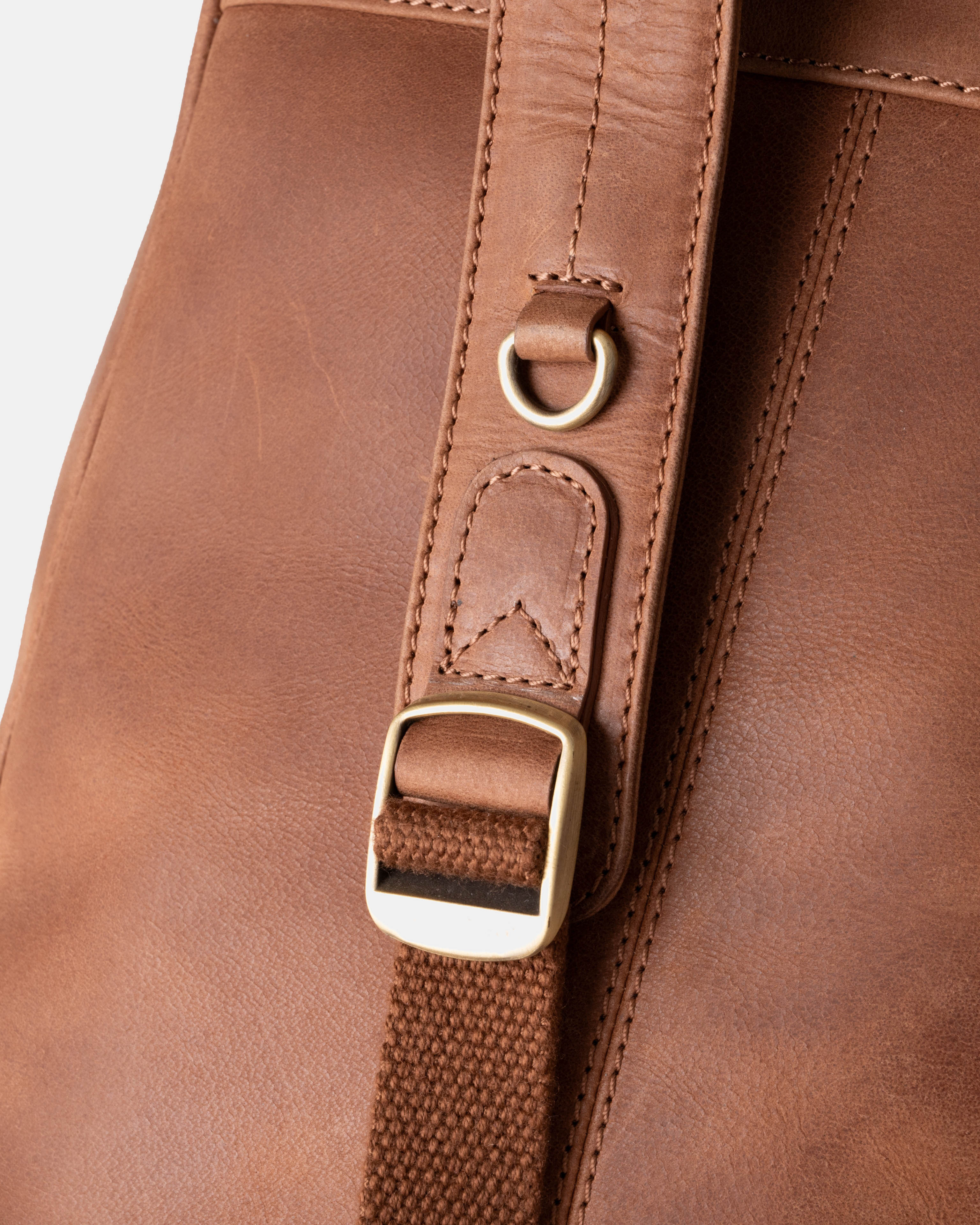 Close-up view of camel backpack strap highlighting a bronze metal adjustment buckle