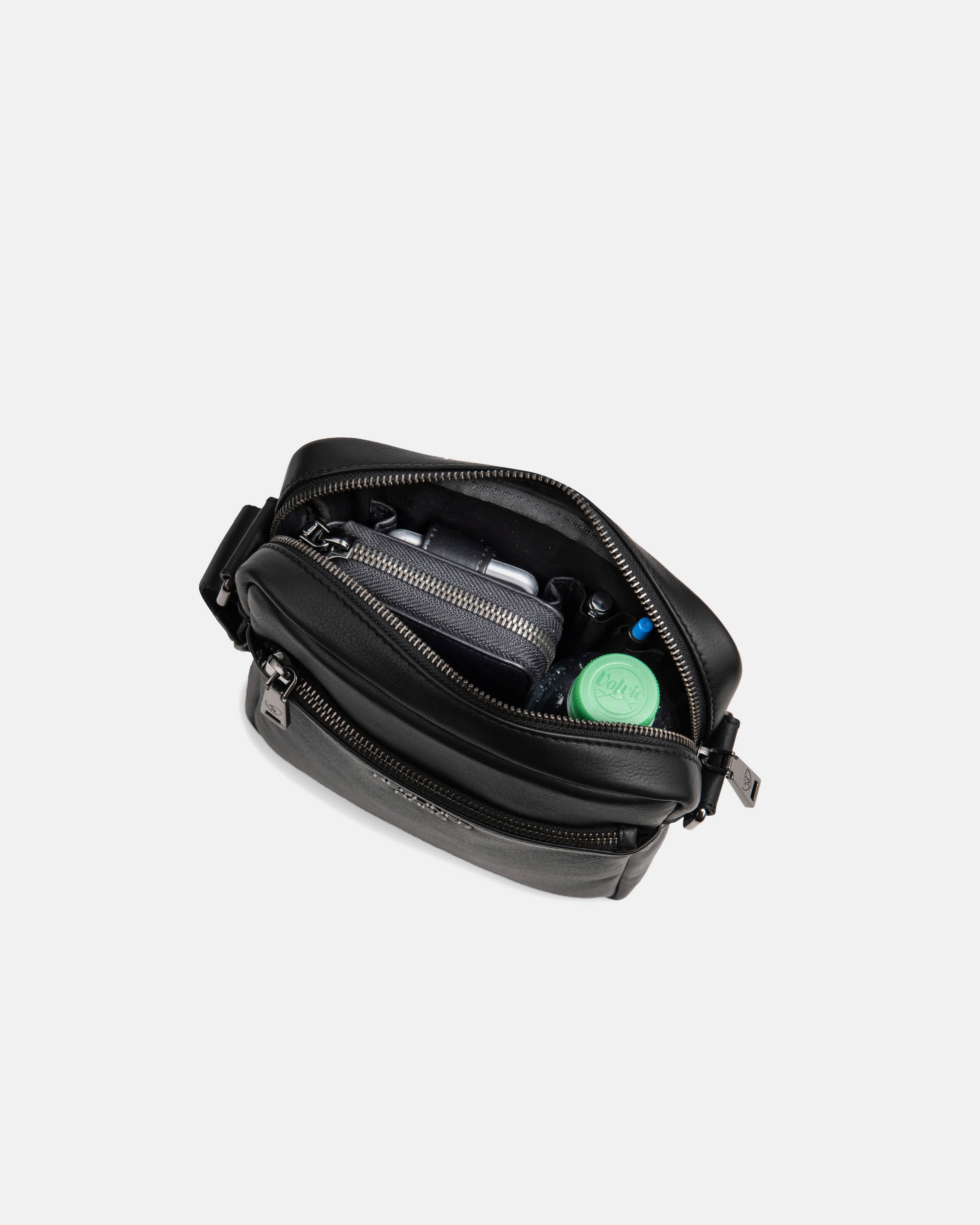 Top-down open view of black leather messenger bag filled with items