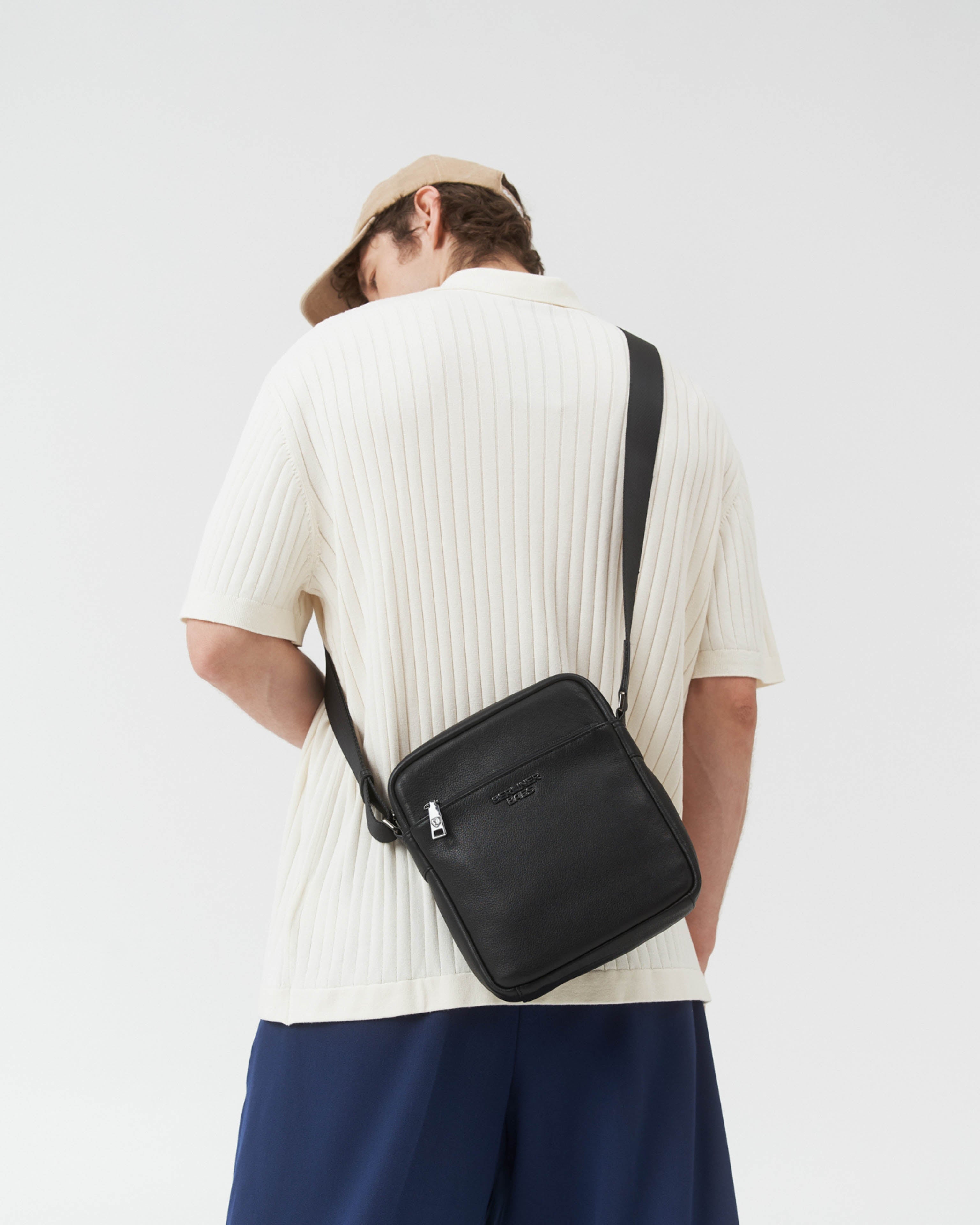 Rear view of man wearing black leather crossbody messenger bag with strap