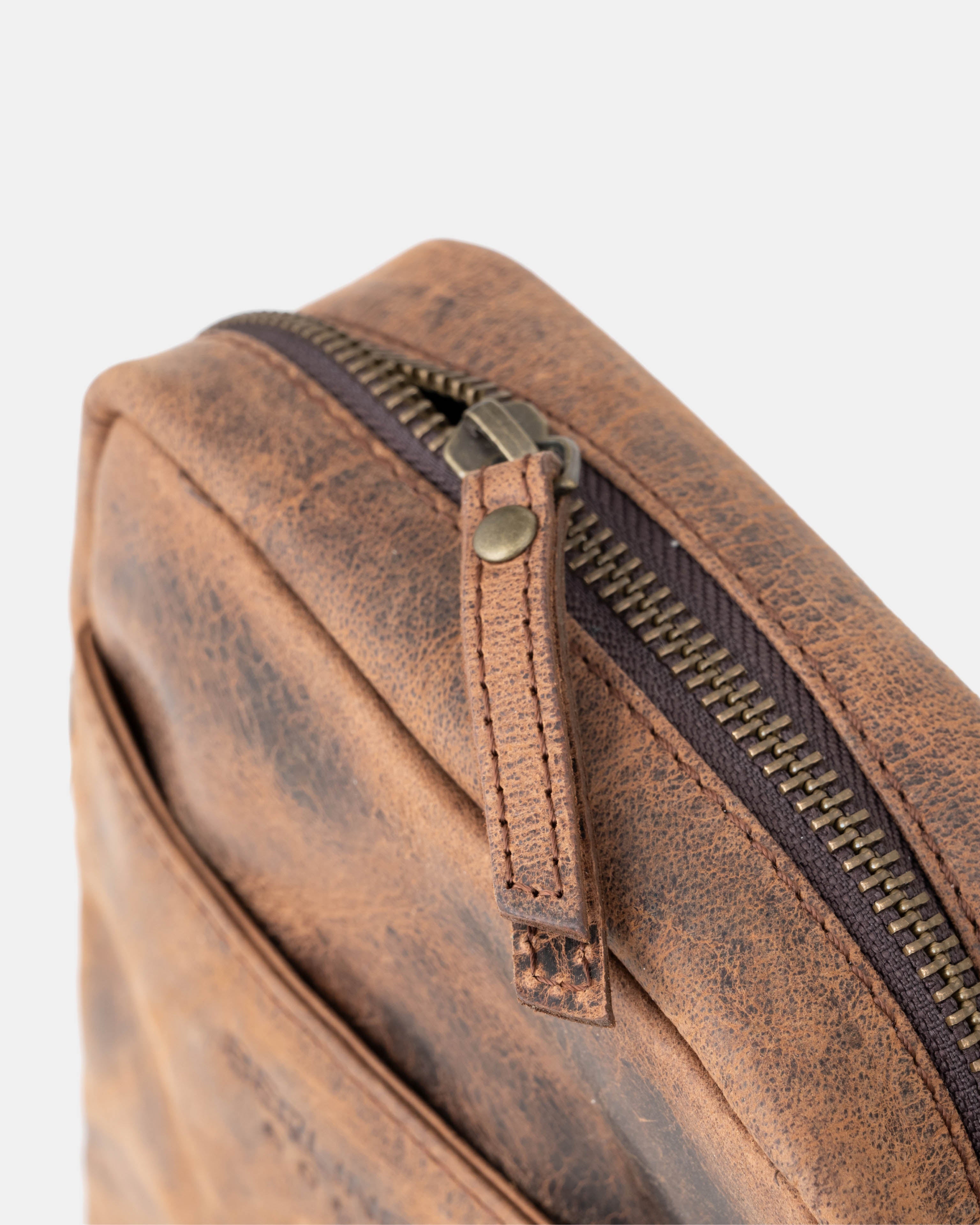 Close up view of the zipper hardware and leather pull on a earth leather messenger bag
