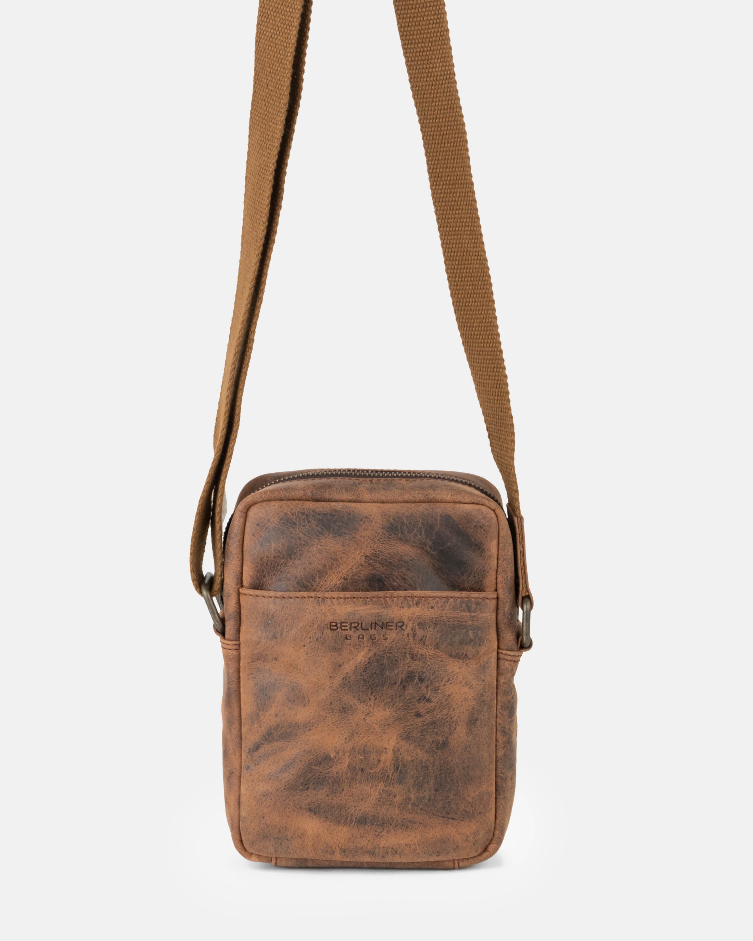 Front view of earth leather messenger bag hanging from its strap
