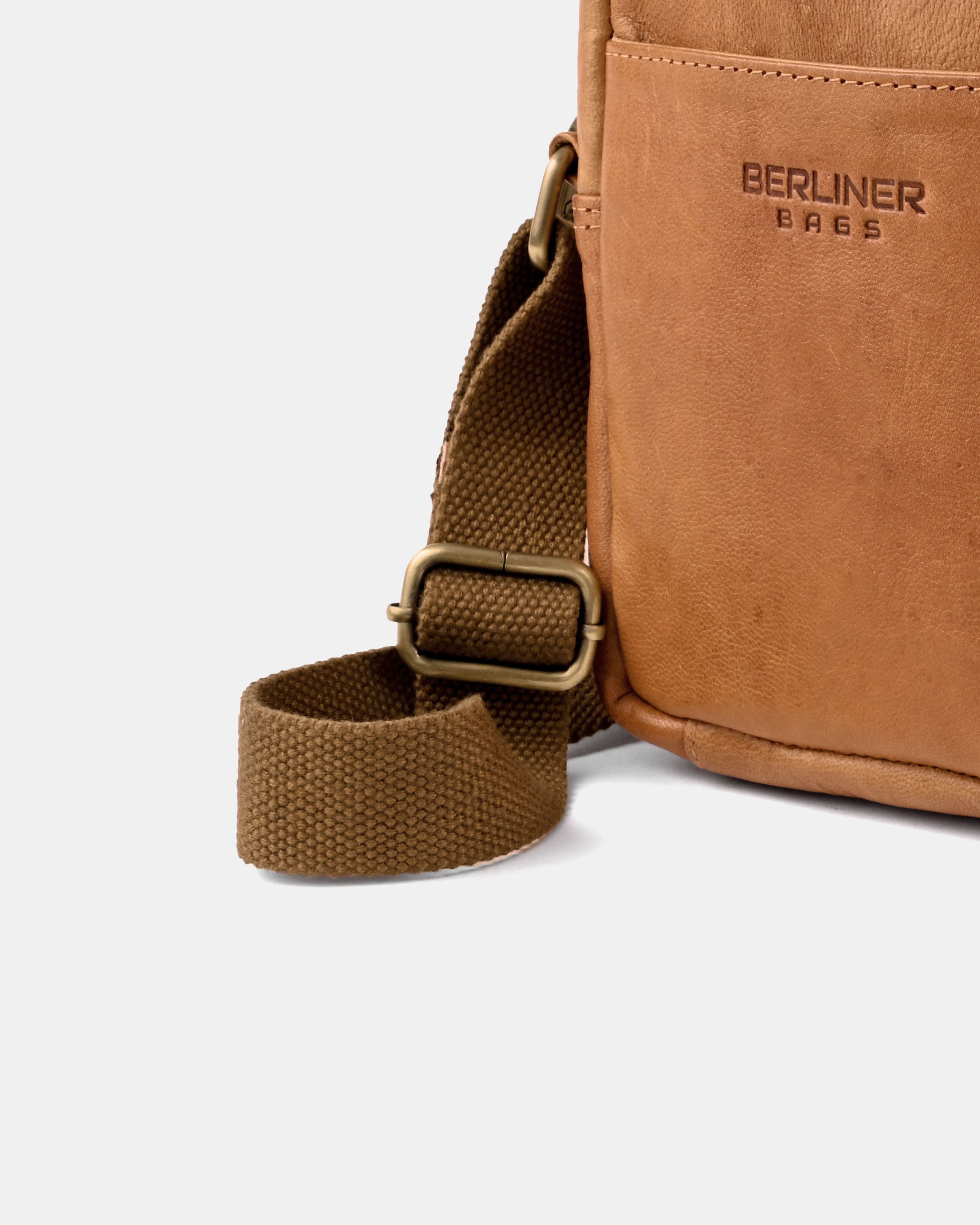 Close up view of the adjustable canvas strap and hardware on a vintage leather messenger bag