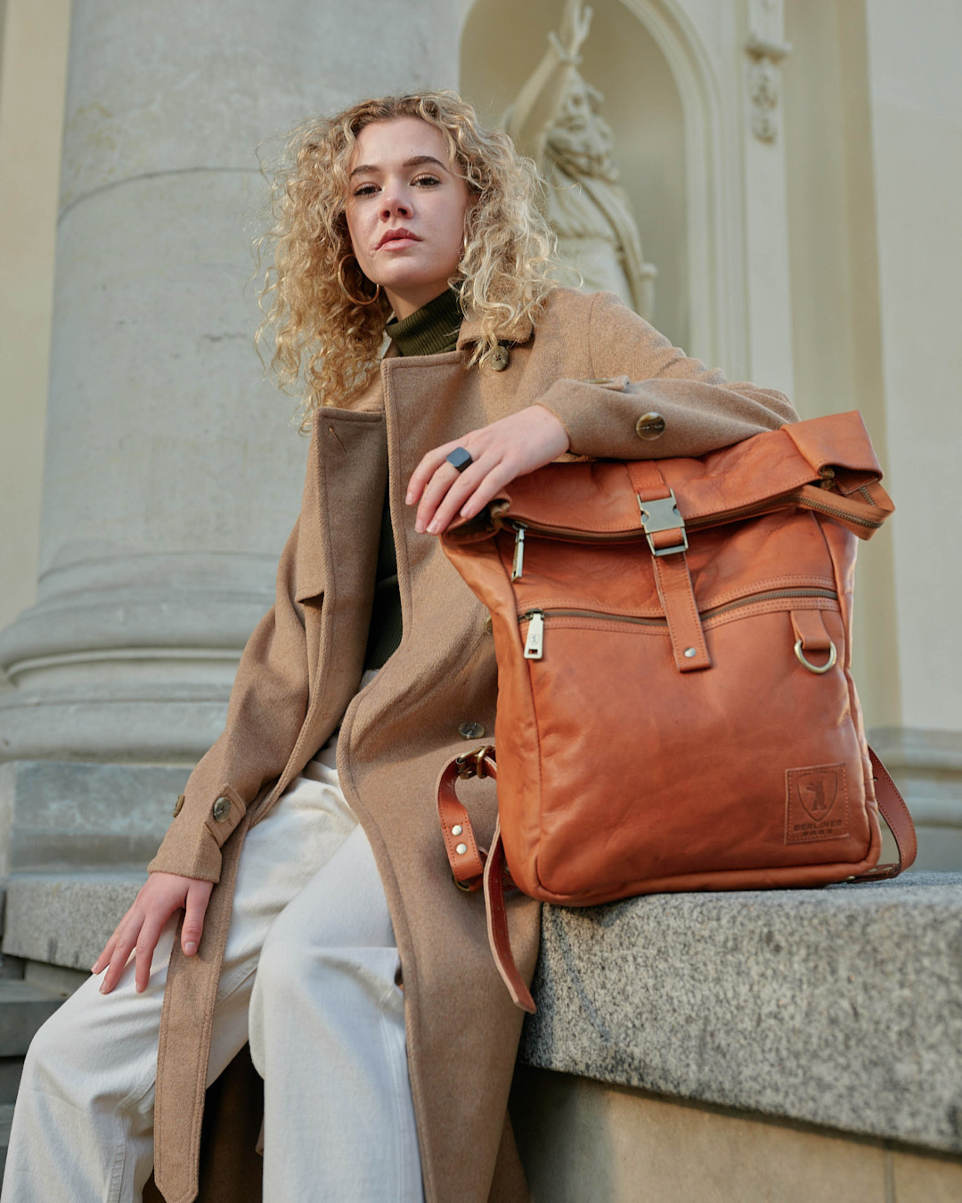 Front view of woman posing with vintage leather backpack bag