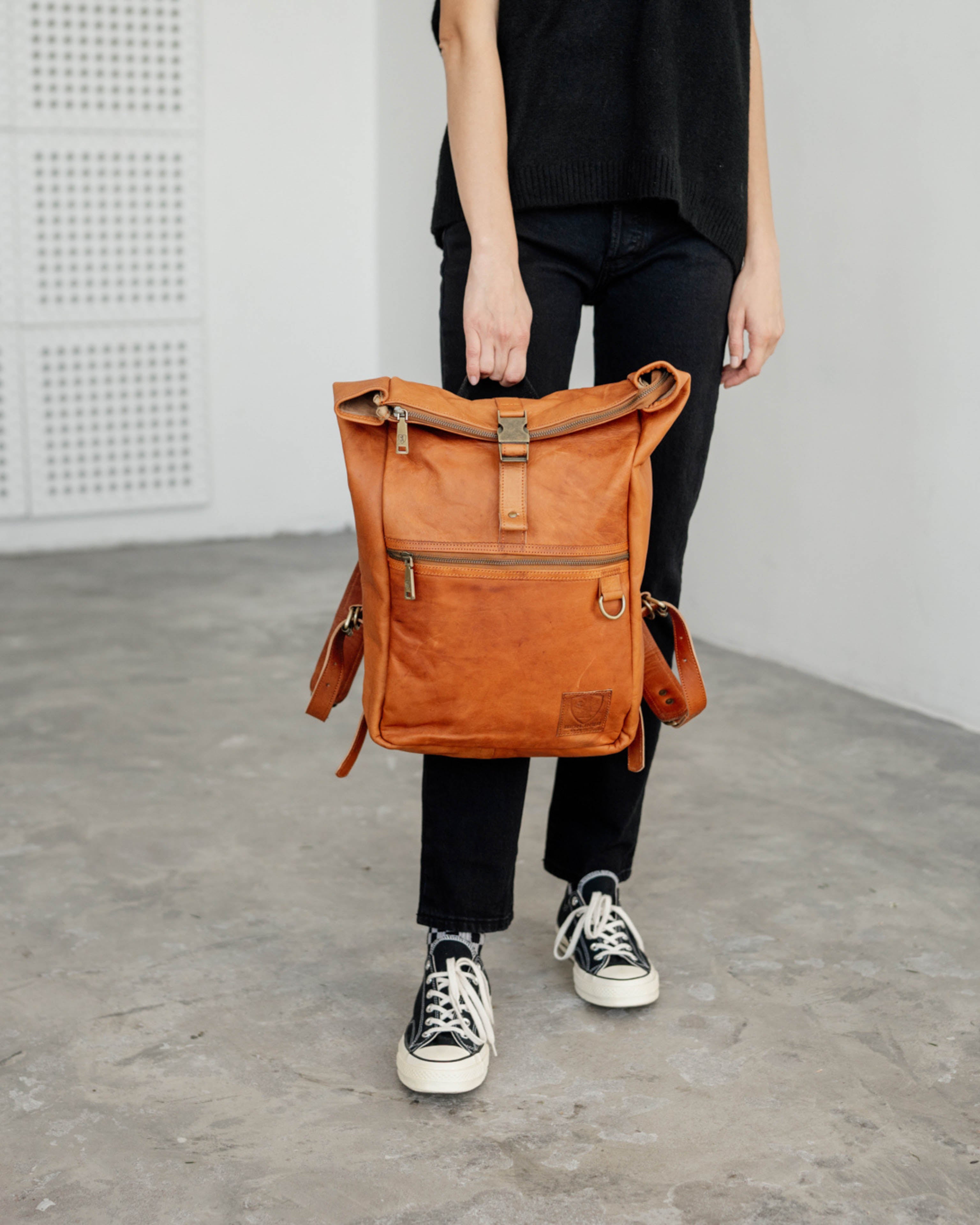 Front view of woman holding vintage leather backpack bag downwards
