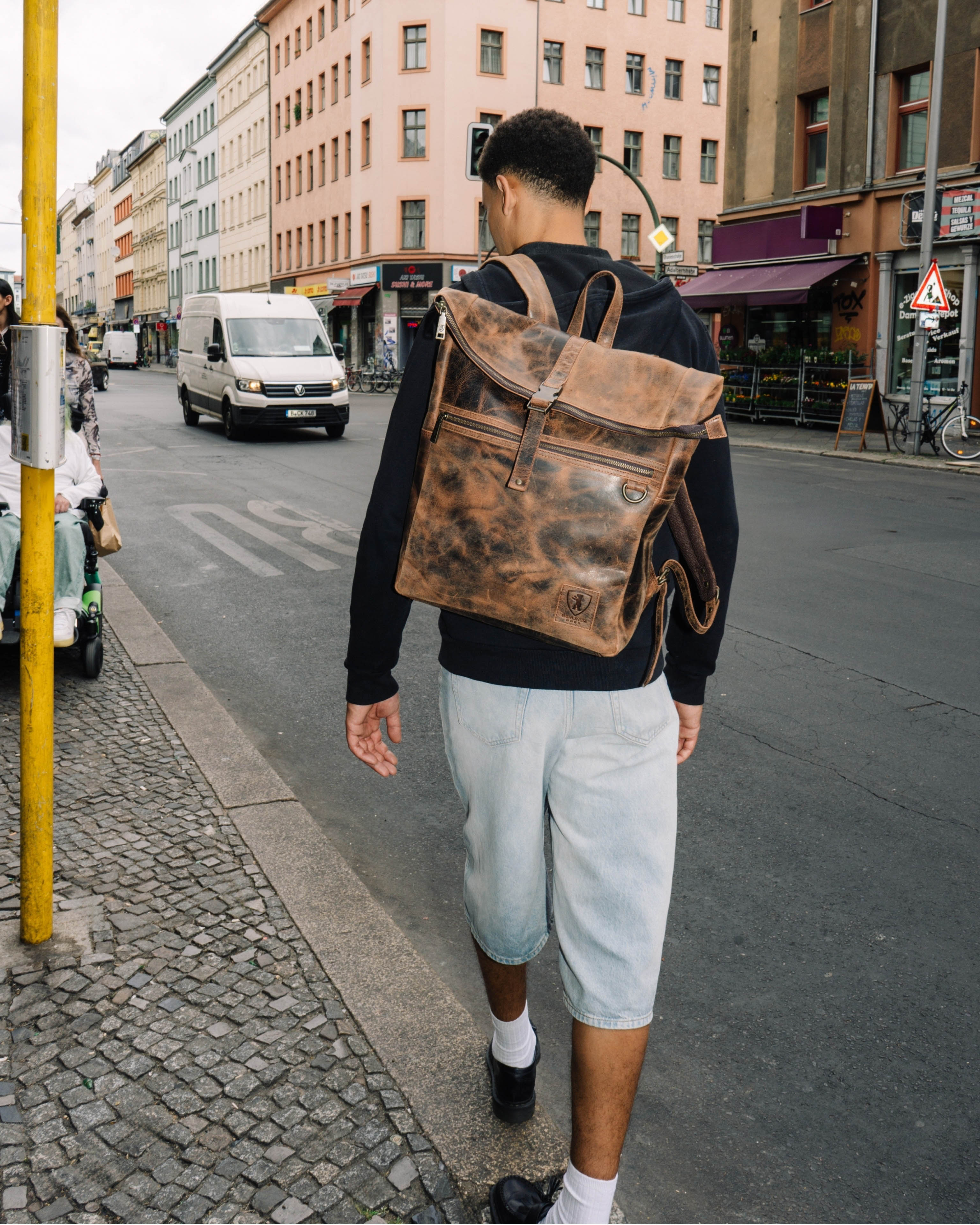 Man walking on city sidewalk wearing earth leather backpack