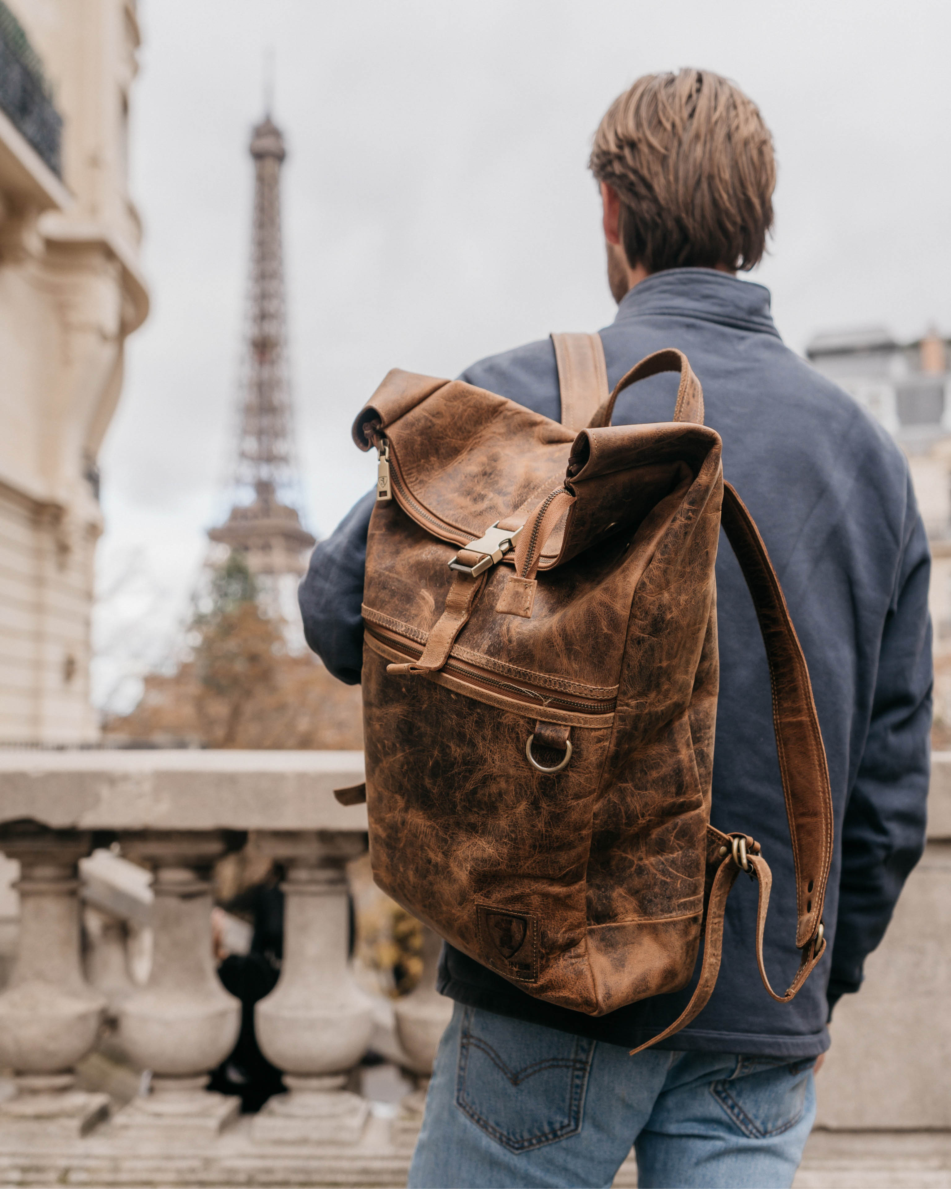 Man wearing walnut leather backpack with Eiffel Tower in background