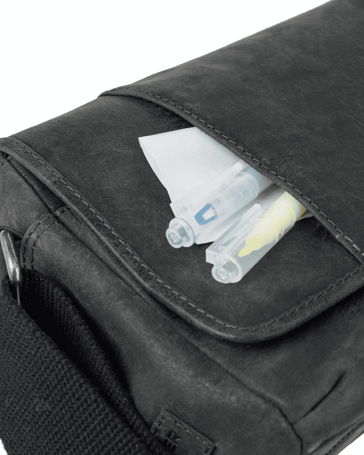 Close-up view of a dark grey leather messenger bag showing pens tucked into a front pocket under the flap