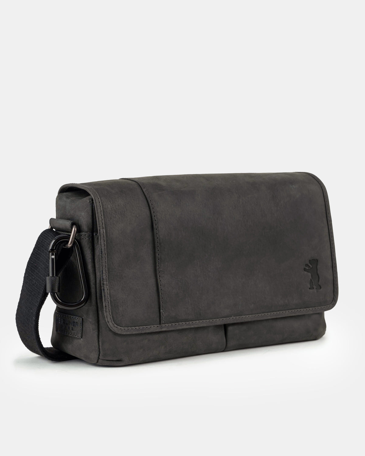Three-quarter front view of a dark grey leather messenger bag with a black carabiner attached to the strap loop