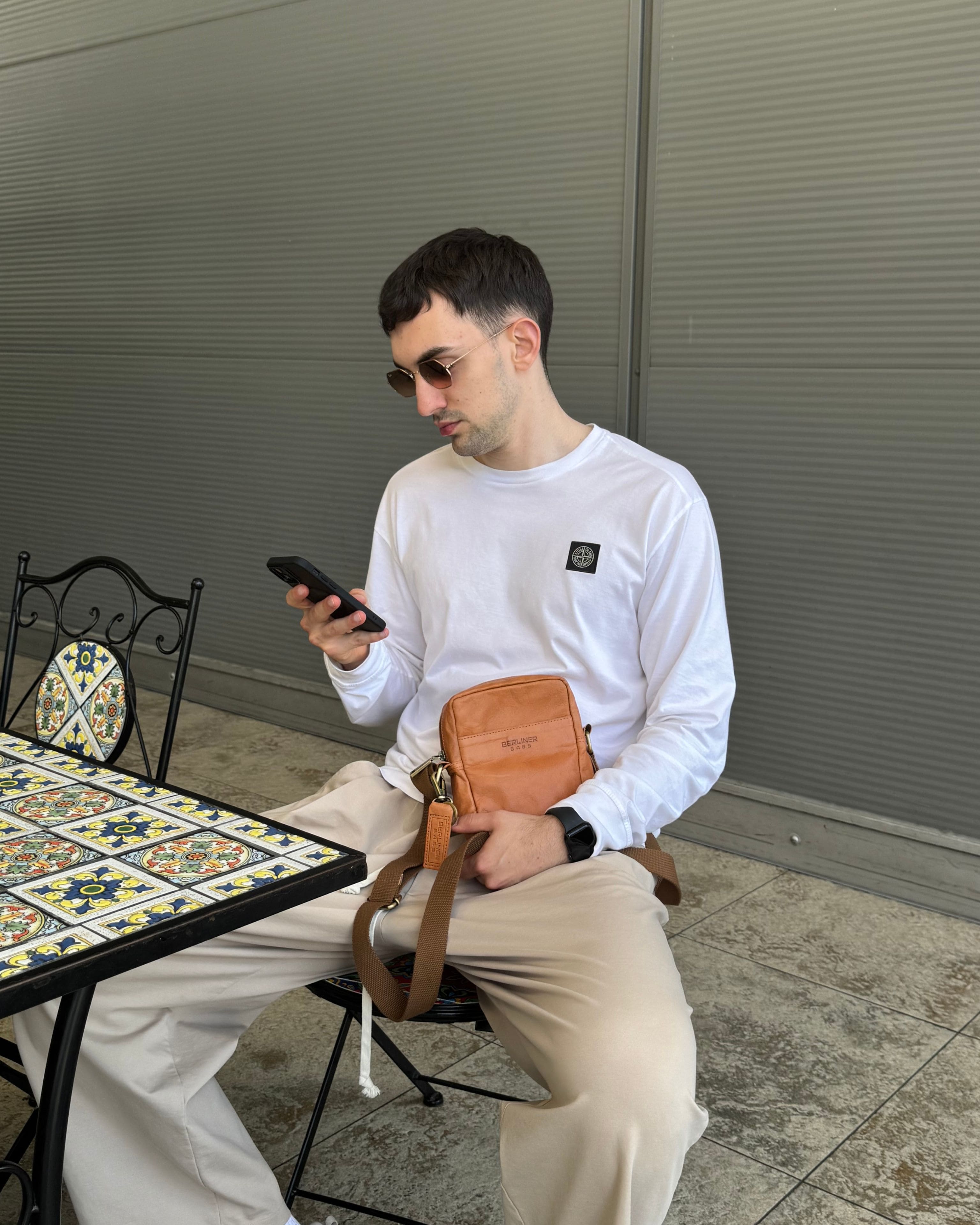 Man sitting at a table wearing a vintage leather messenger bag with a strap