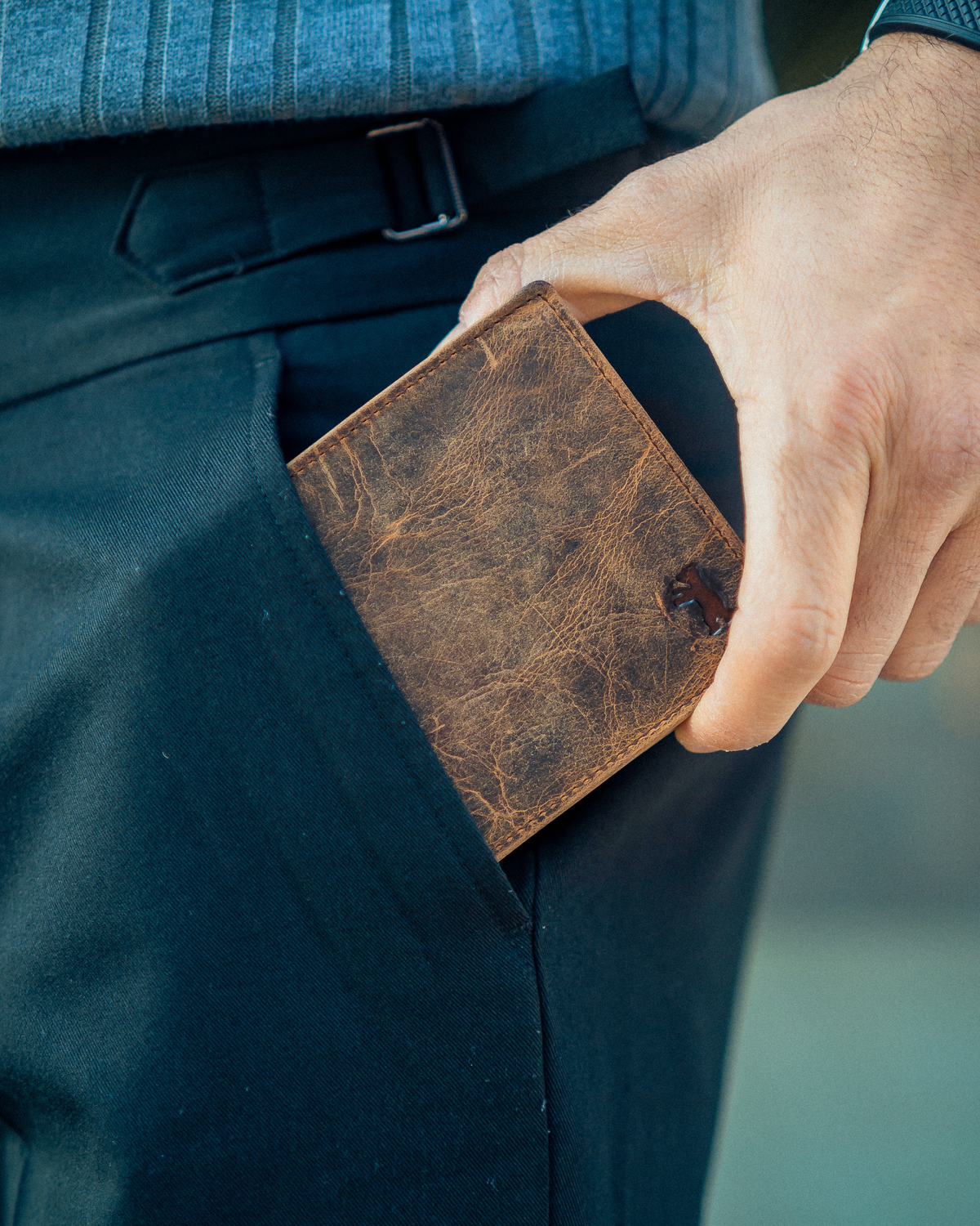 Hand putting  a walnut leather wallet with ID flap in to the pocket