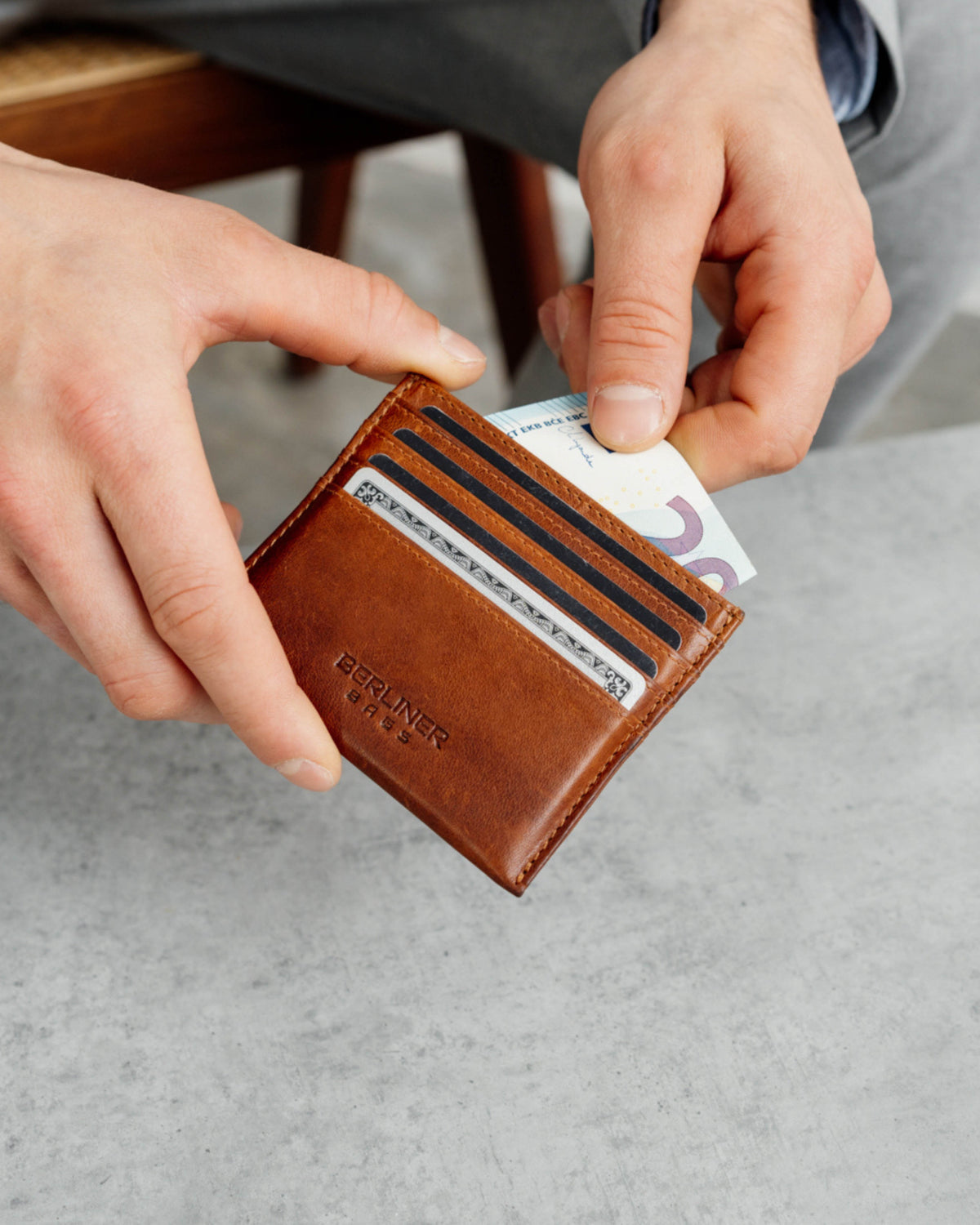 Man taking money out of a cognac leather card case.