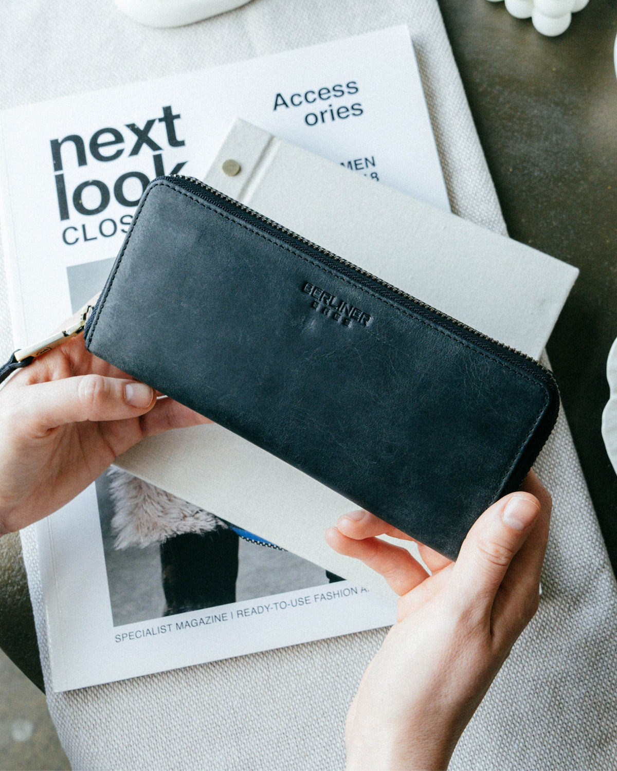 Person showing front view of dark grey leather wallet