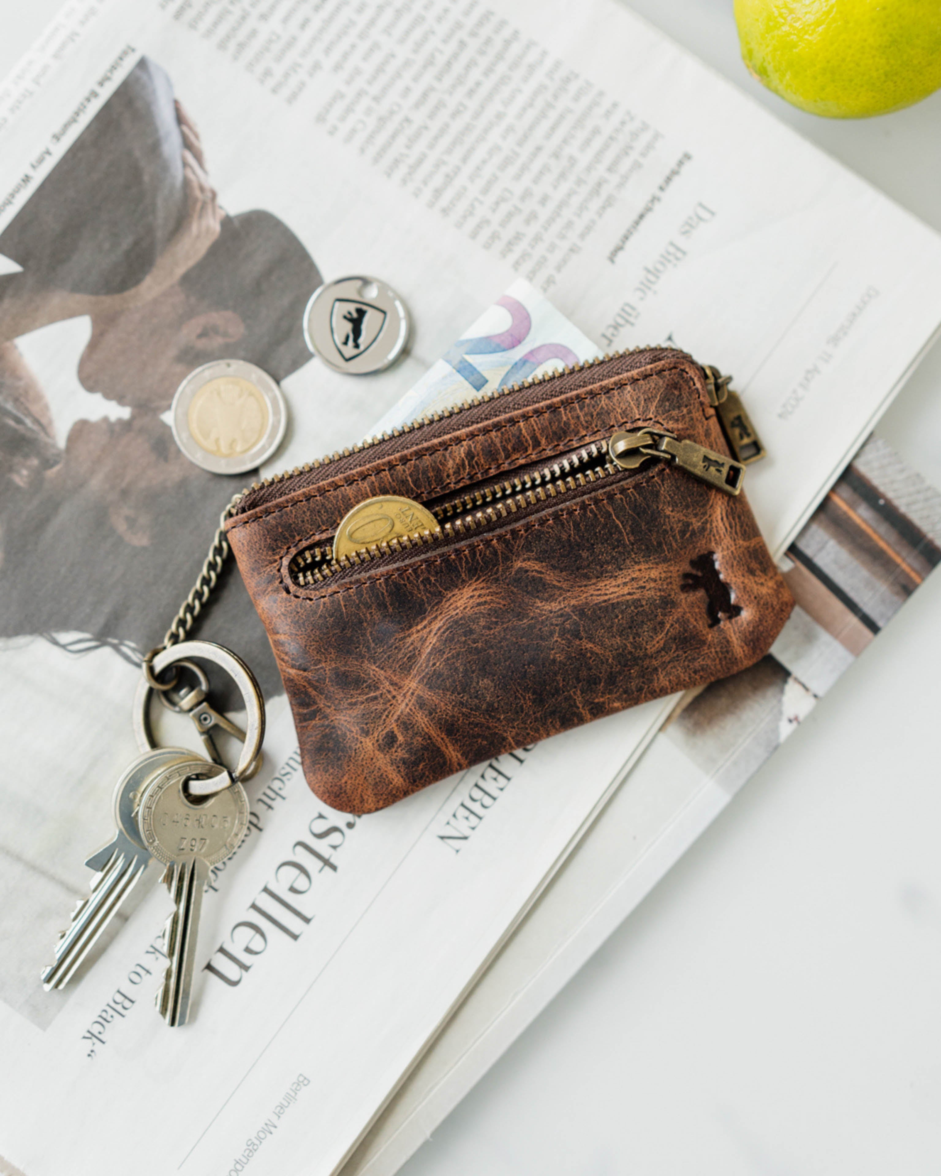 Earth leather key pouch with coins and keys on a newspaper