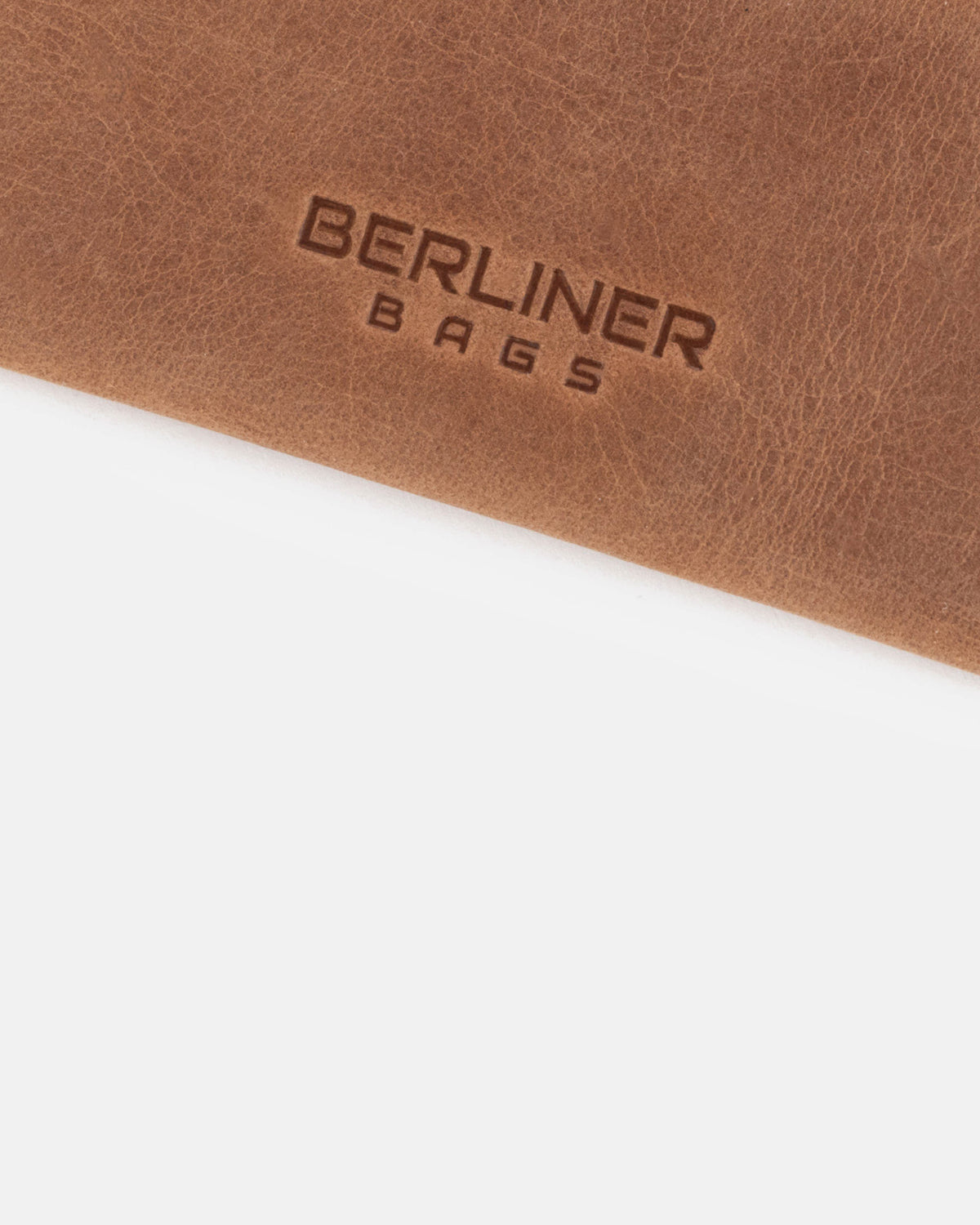 Close-up of a camel leather card case with brand logo