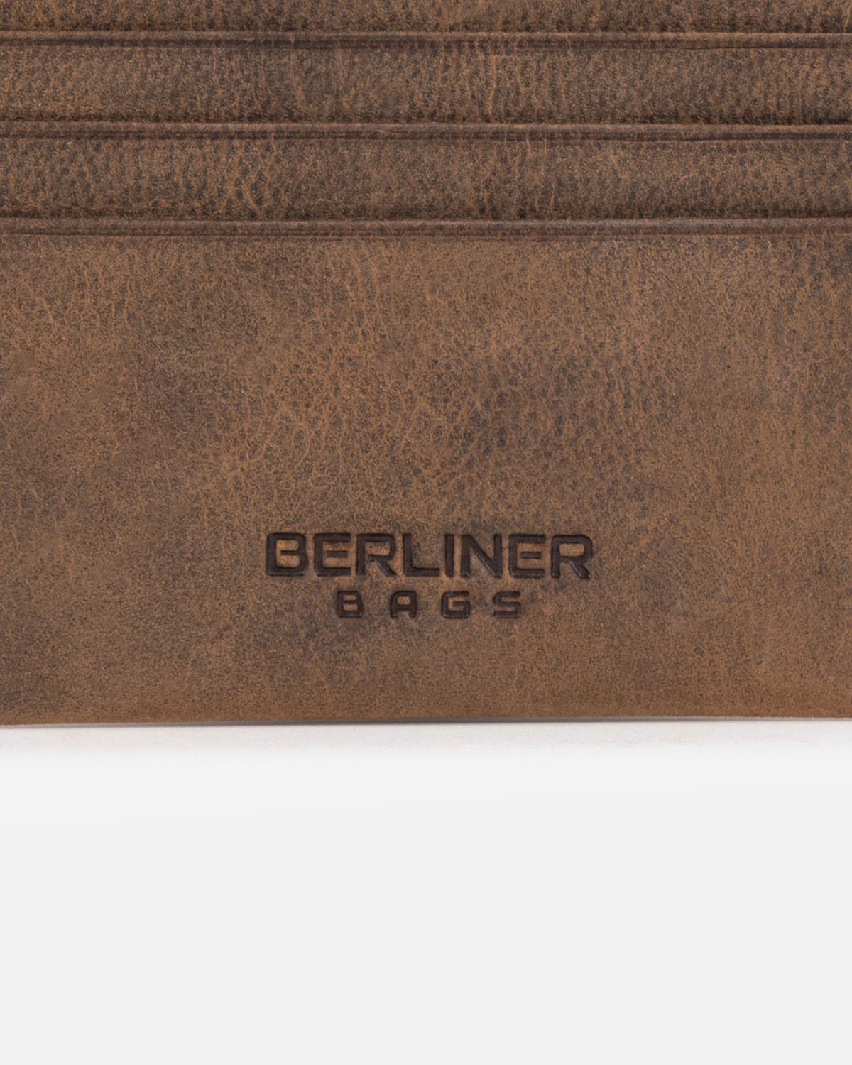 Close-up of espresso leather card case surface with logo.