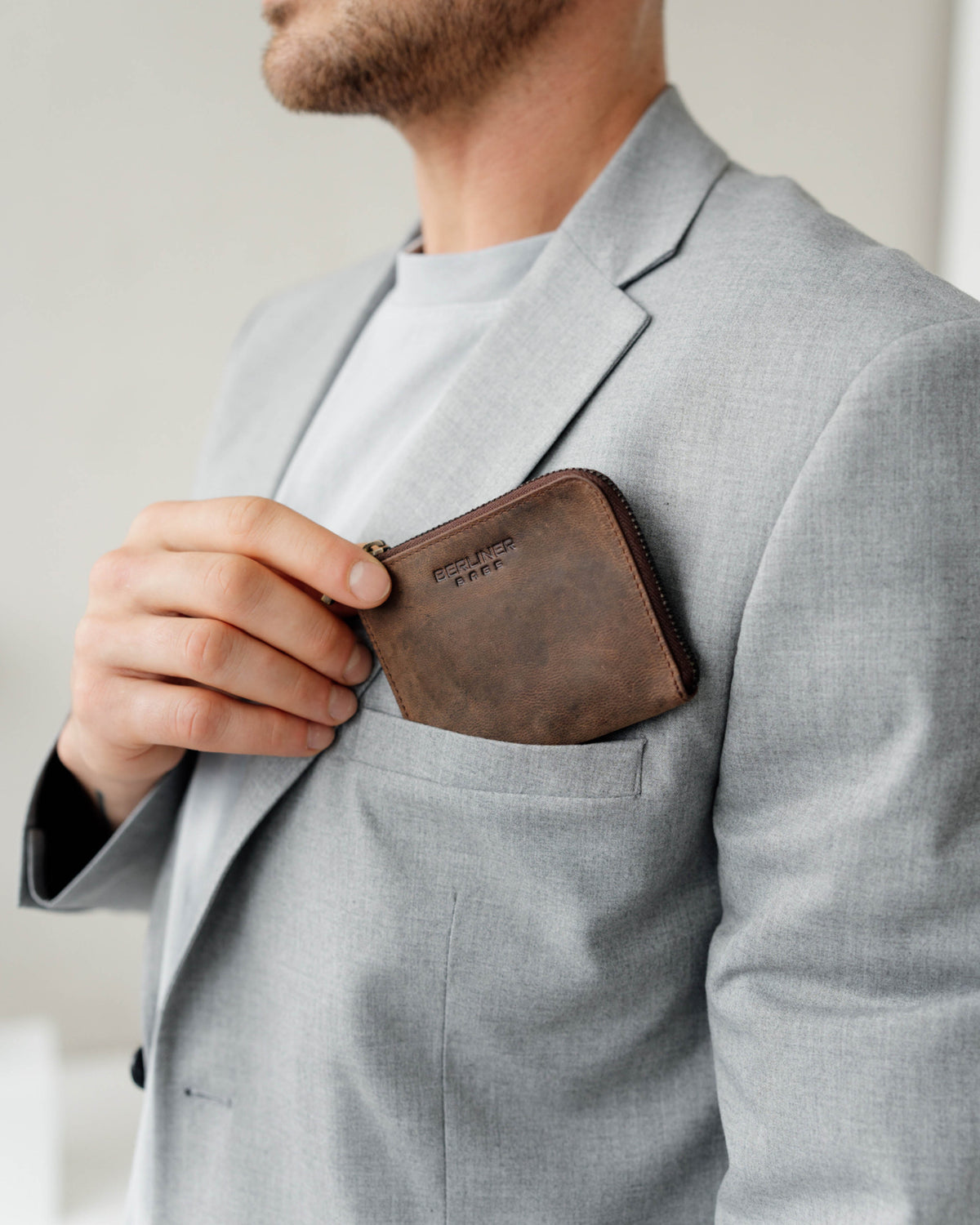 Man putting espresso leather wallet in to the pocket