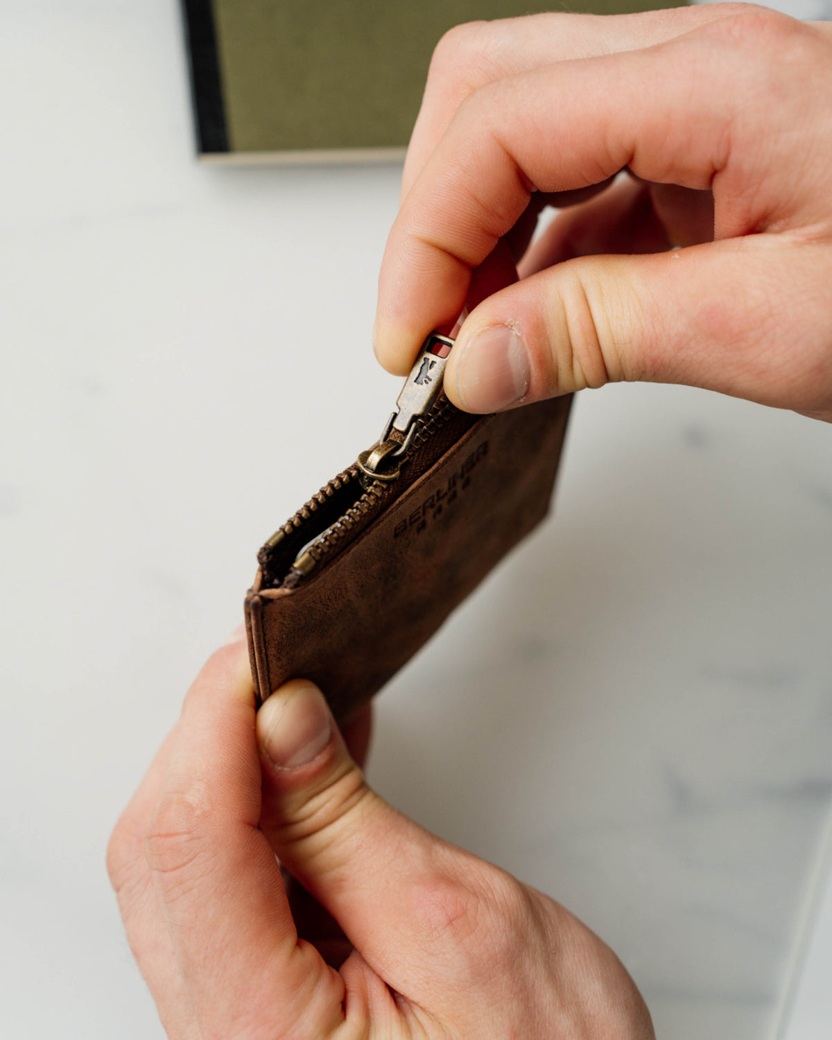 Person opening a espresso leather wallet