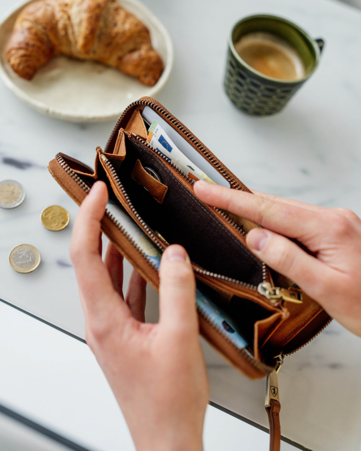 Hands opening suede cognac leather wallet with cash inside