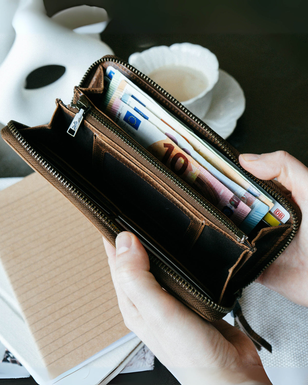 Person holding a walnut leather wallet filled with cash bills