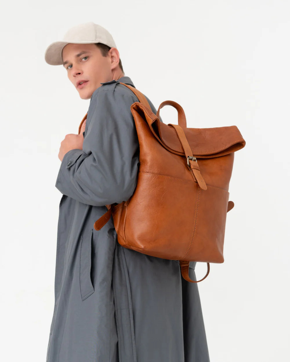 Man wearing vintage leather roll-top backpack with center strap.