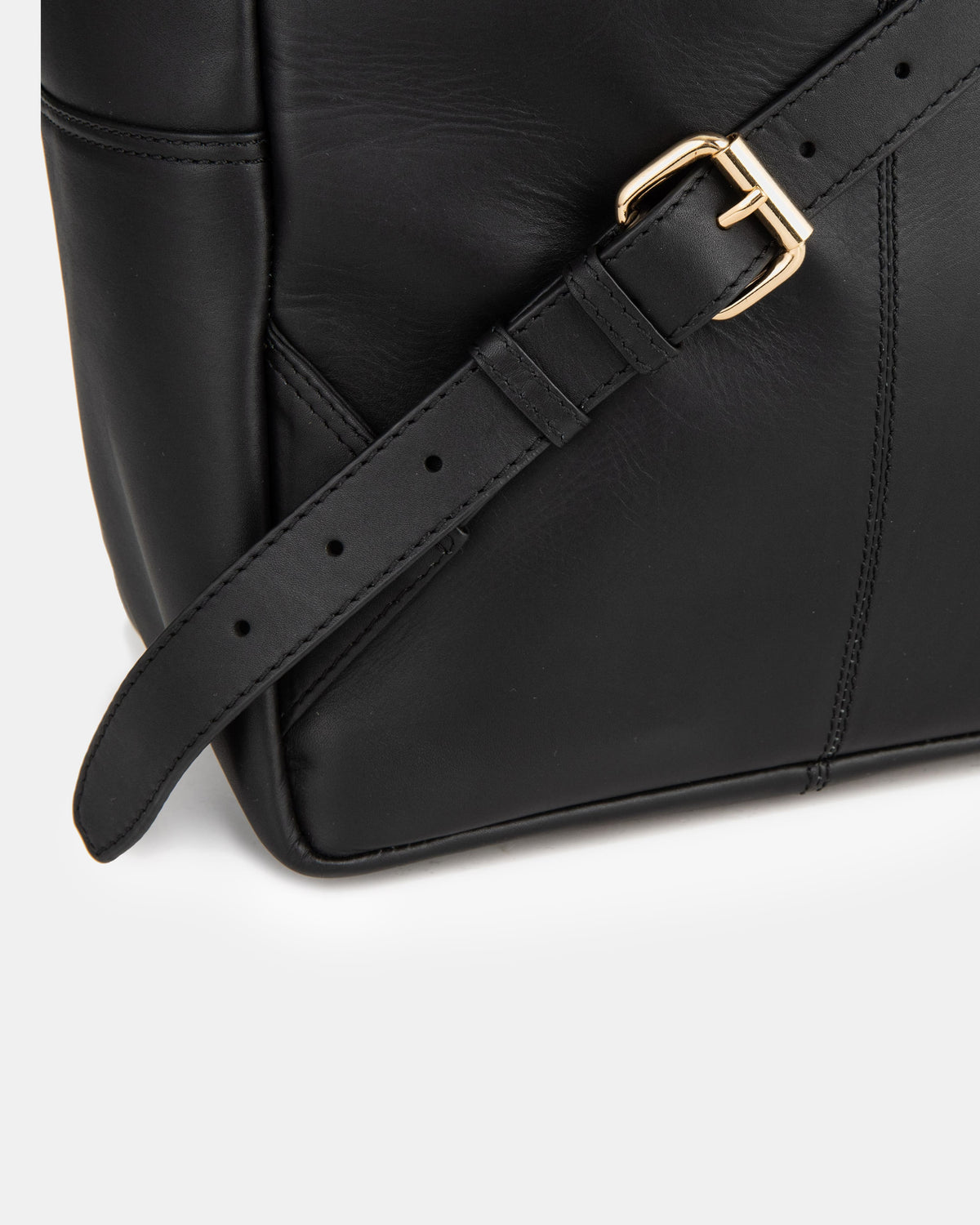 Close-up of black backpack strap featuring a gold roller buckle