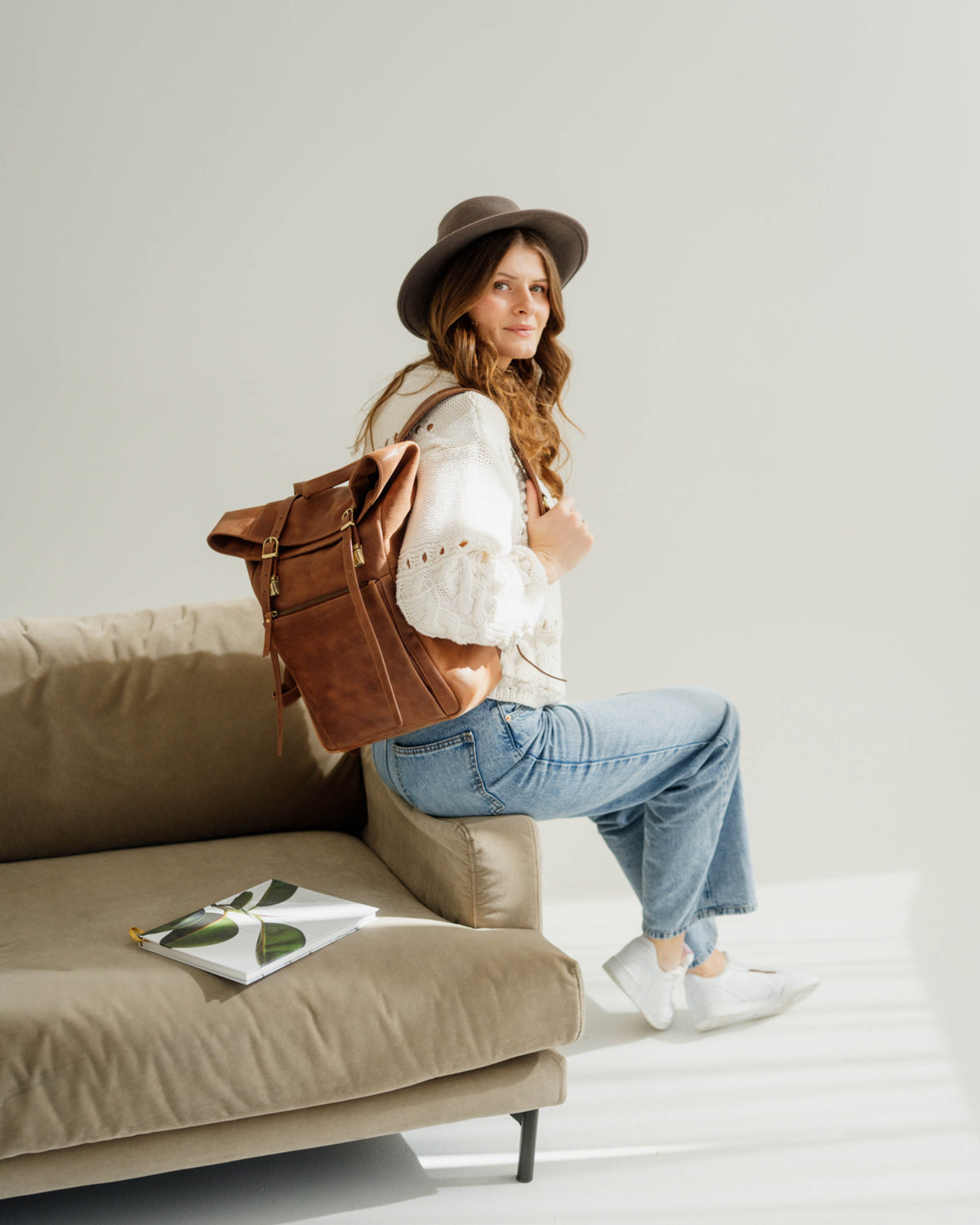 Woman wearing hat and camel roll-top backpack