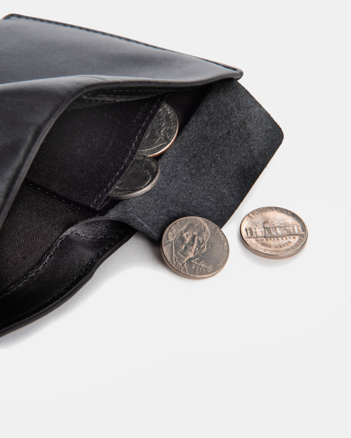 A close-up of a emboss leather wallet compartment containing metal coins.