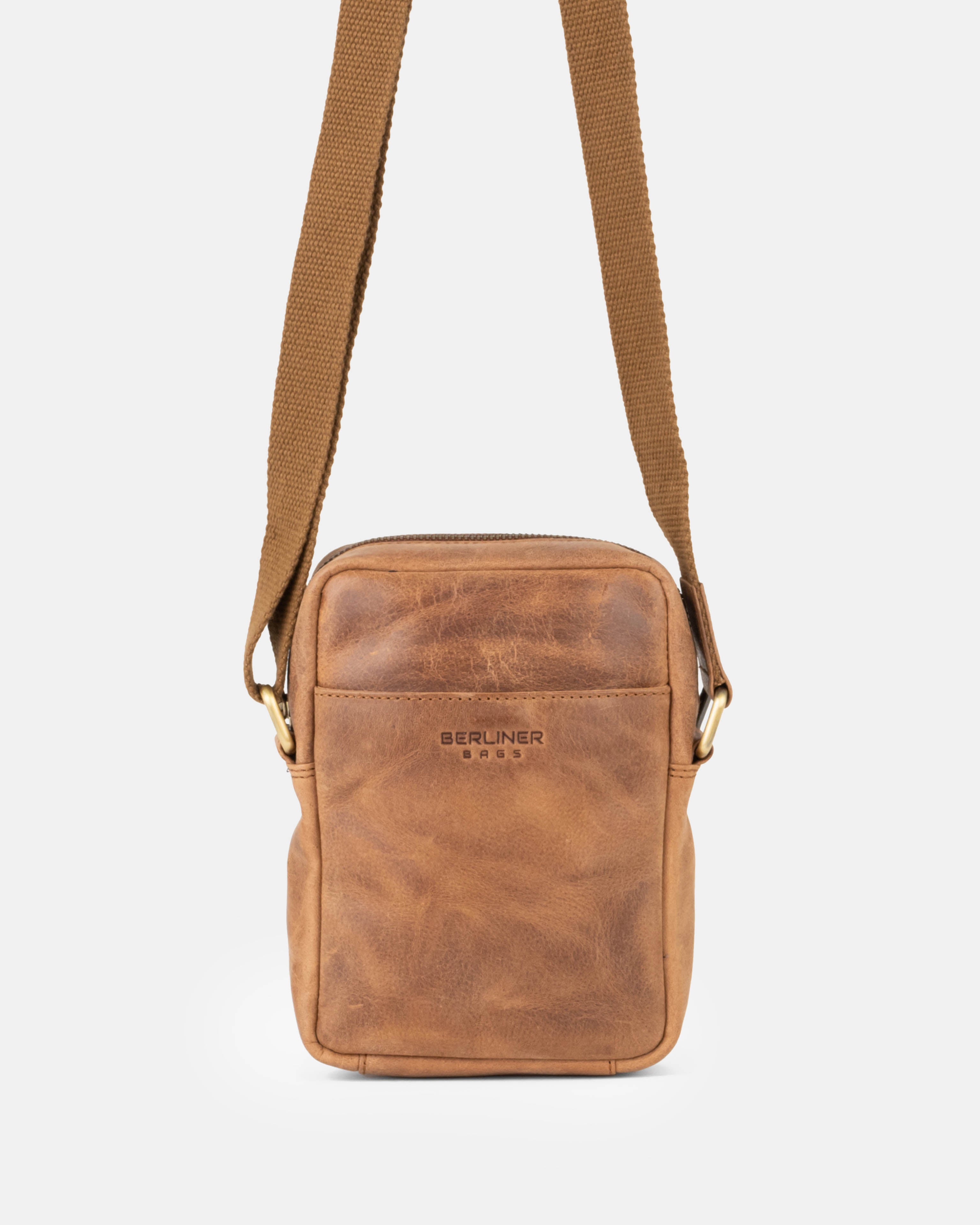 Front view of camel leather messenger bag hanging from its strap