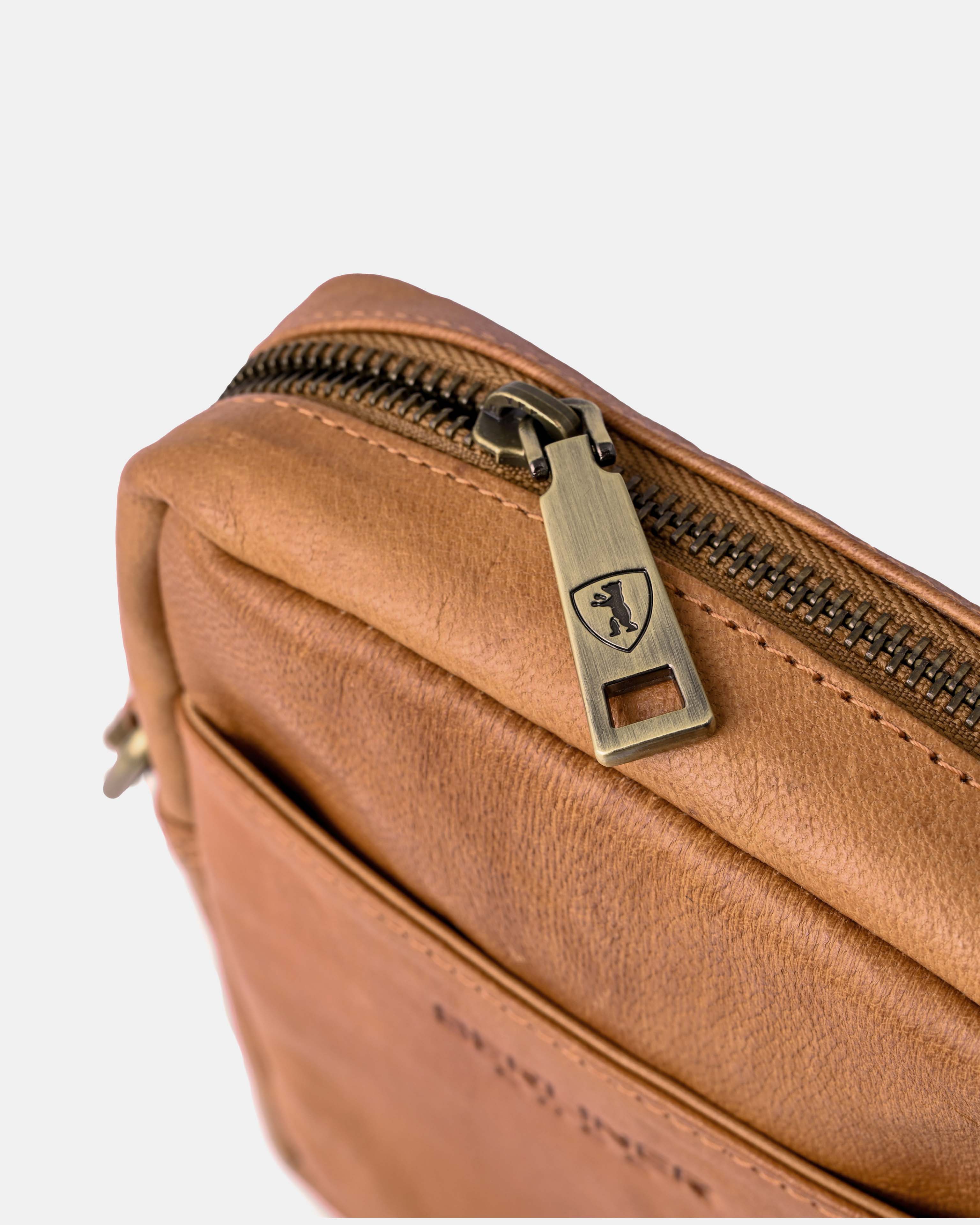 Close up view of the zipper hardware on a vintage  leather messenger bag