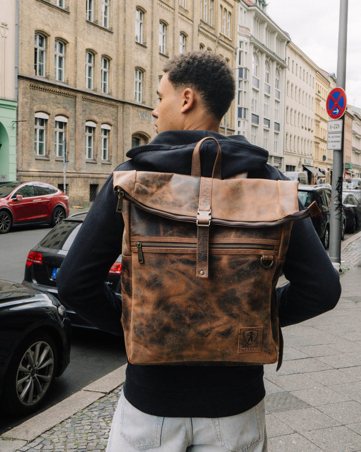 Man standing on city sidewalk wearing earth leather backpack