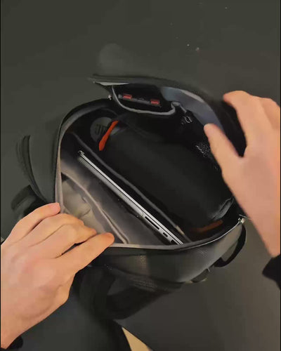 An interior view of a black backpack showing organized storage compartments and a laptop